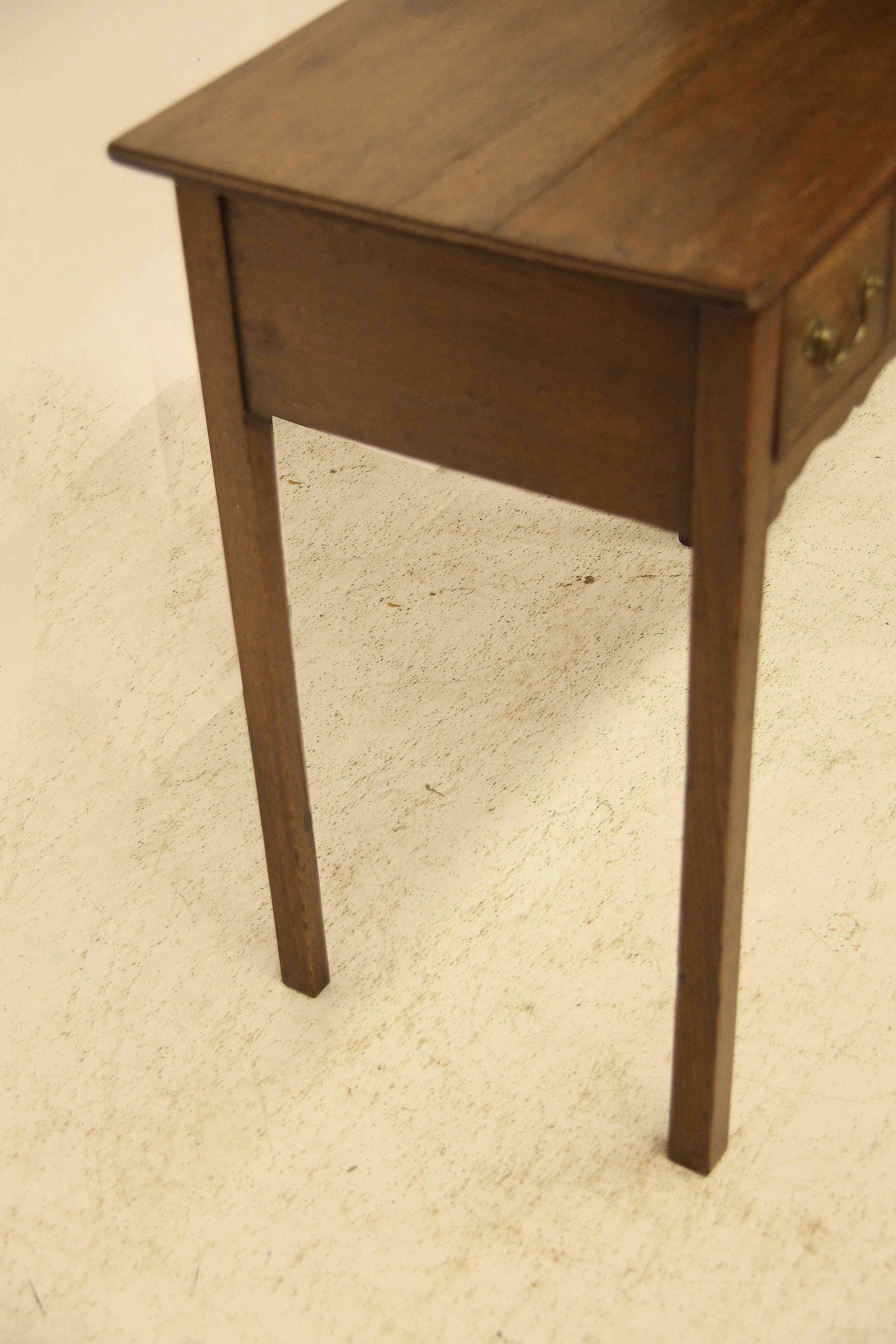 English oak three drawer side table, the top with molded edge above three drawers cross banded with mahogany, original swan neck brass pulls, nicely shaped apron and slender tapered legs.