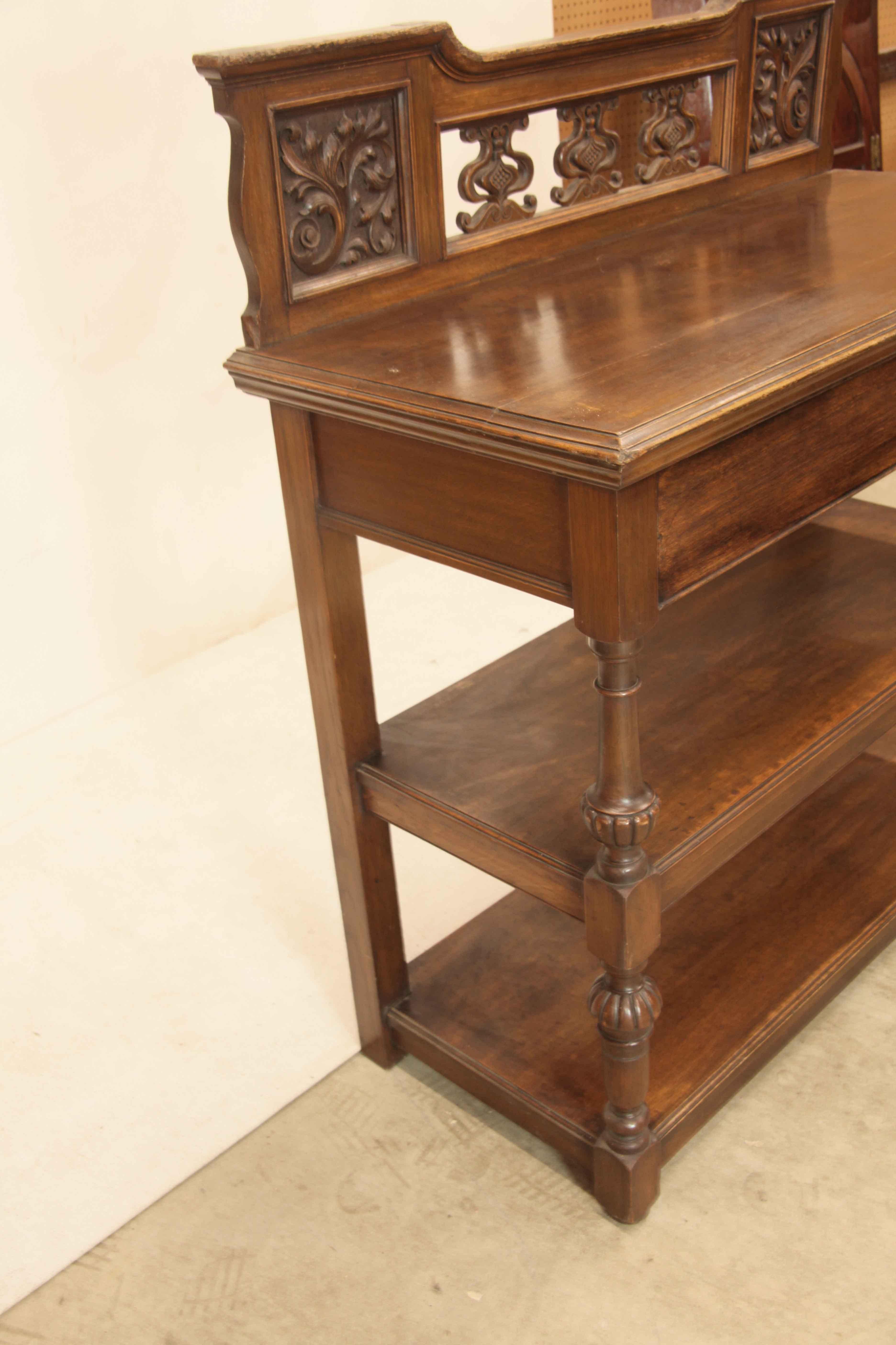 English oak three tier buffet,  the back gallery features square panels of stylized foliage and volutes at each end with three whimsical carved motifs in the center,  top has nice oak color and patina with molding around the front and sides; lower