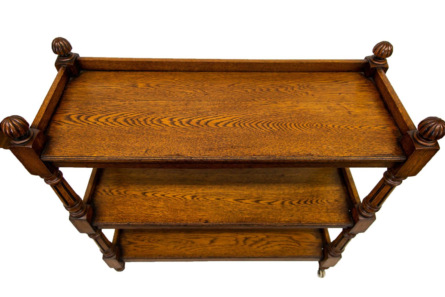 The three tiers of this server have galleries on the back and sides. The front edge of each shelf has a carved beaded molding. The top has four reeded mushroom finials. The shelf supports are turned and fluted. The lower legs terminate in the