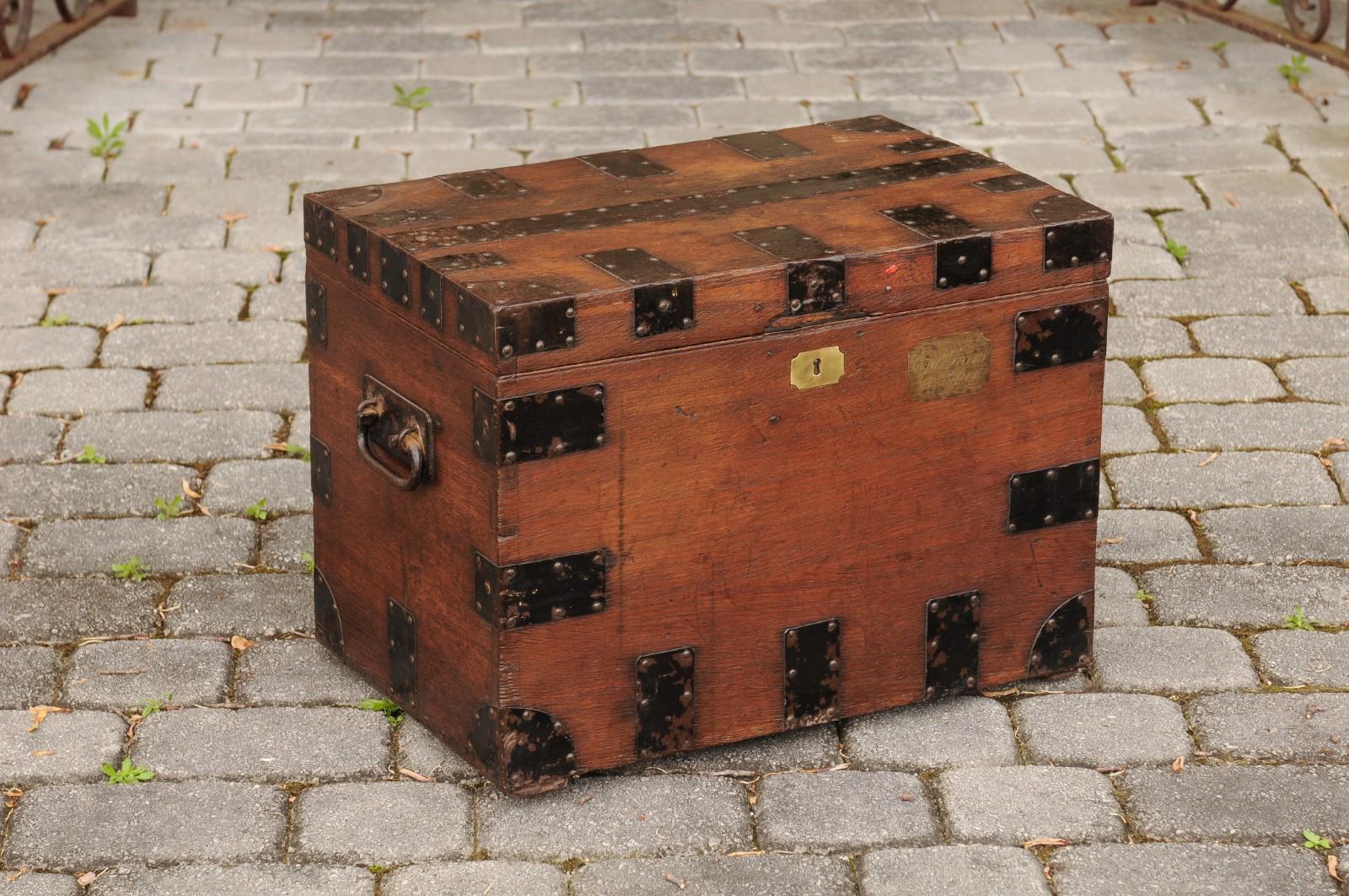 An English oak trunk from the late 19th century, with metal accents and lateral handles. Born in England during the last decade of the 19th century, this handsome oak trunk features a linear Silhouette, regularly accented with metal braces. The lid