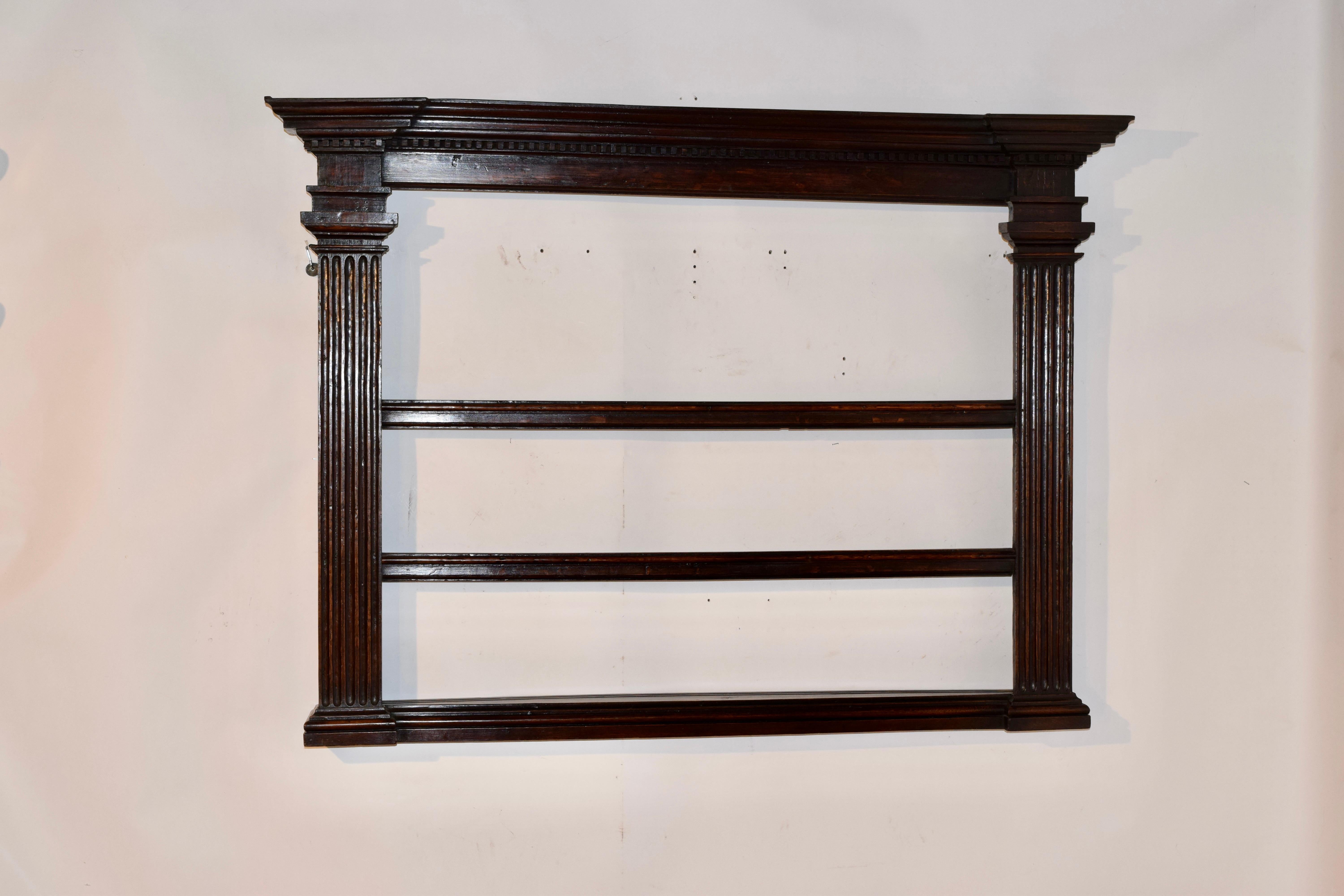 Late 18th century oak wall shelf from England. The top has an elegant crown with dentil molding, over  two columned side panels, joined by flat wall supports on the back and three shelves.  The top and the base are stepped out for added interest and