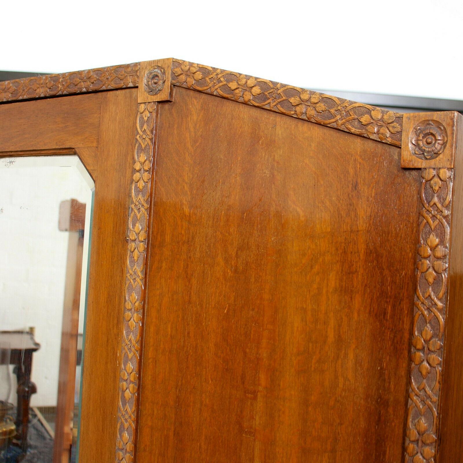 An impressive early 20th century oak wardrobe.

The arched main body fitted a bevelled mirrored door - surrounded by intricately decorated borders - and enclosed two hanging rails and hooks to the interior. Fitted a drawer to the base mounted with