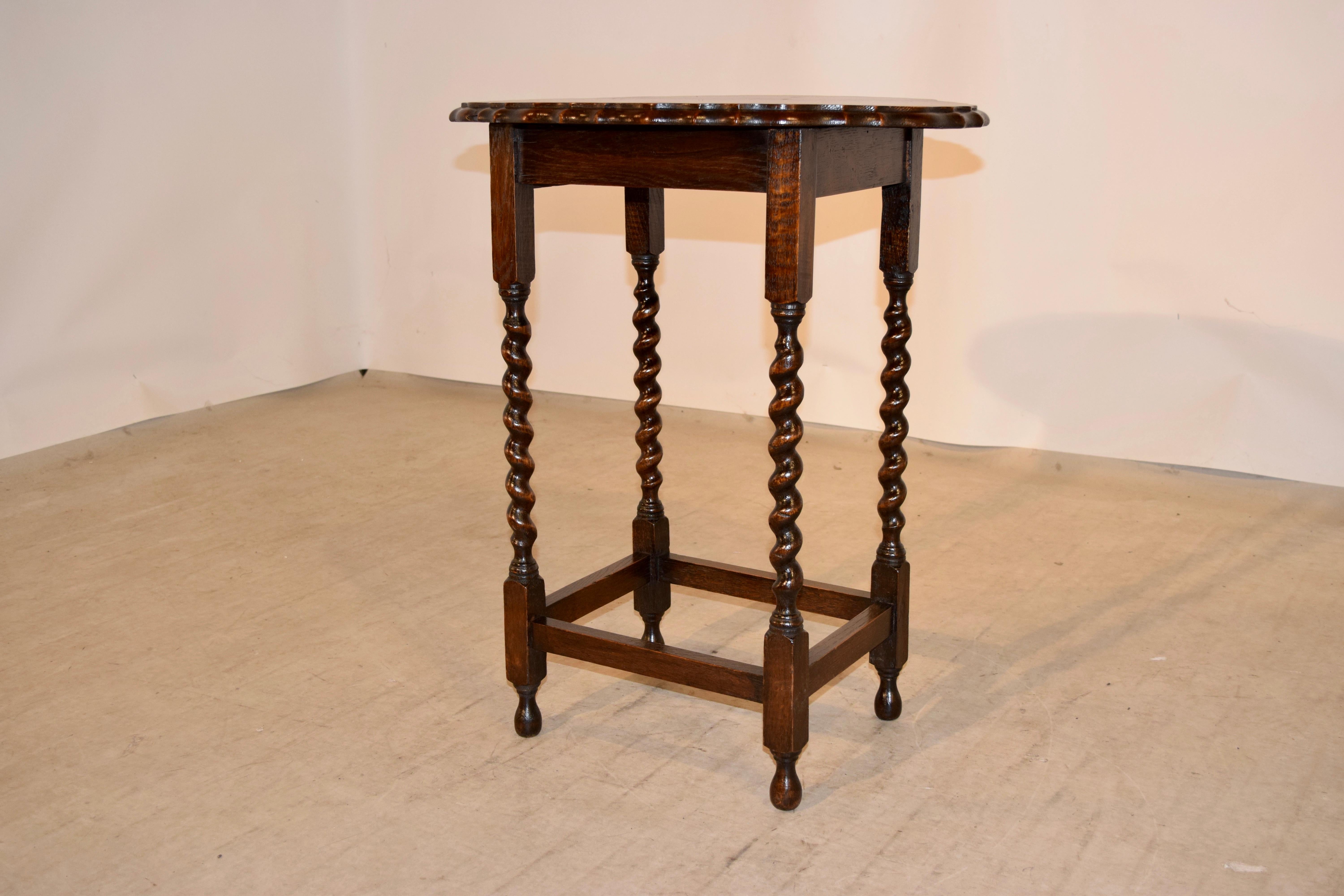 English oak occasional table with a scalloped and beveled edge around the oval top, following down to a simple apron and supported on hand-turned barley twist legs joined by stretchers and raised on hand-turned feet.