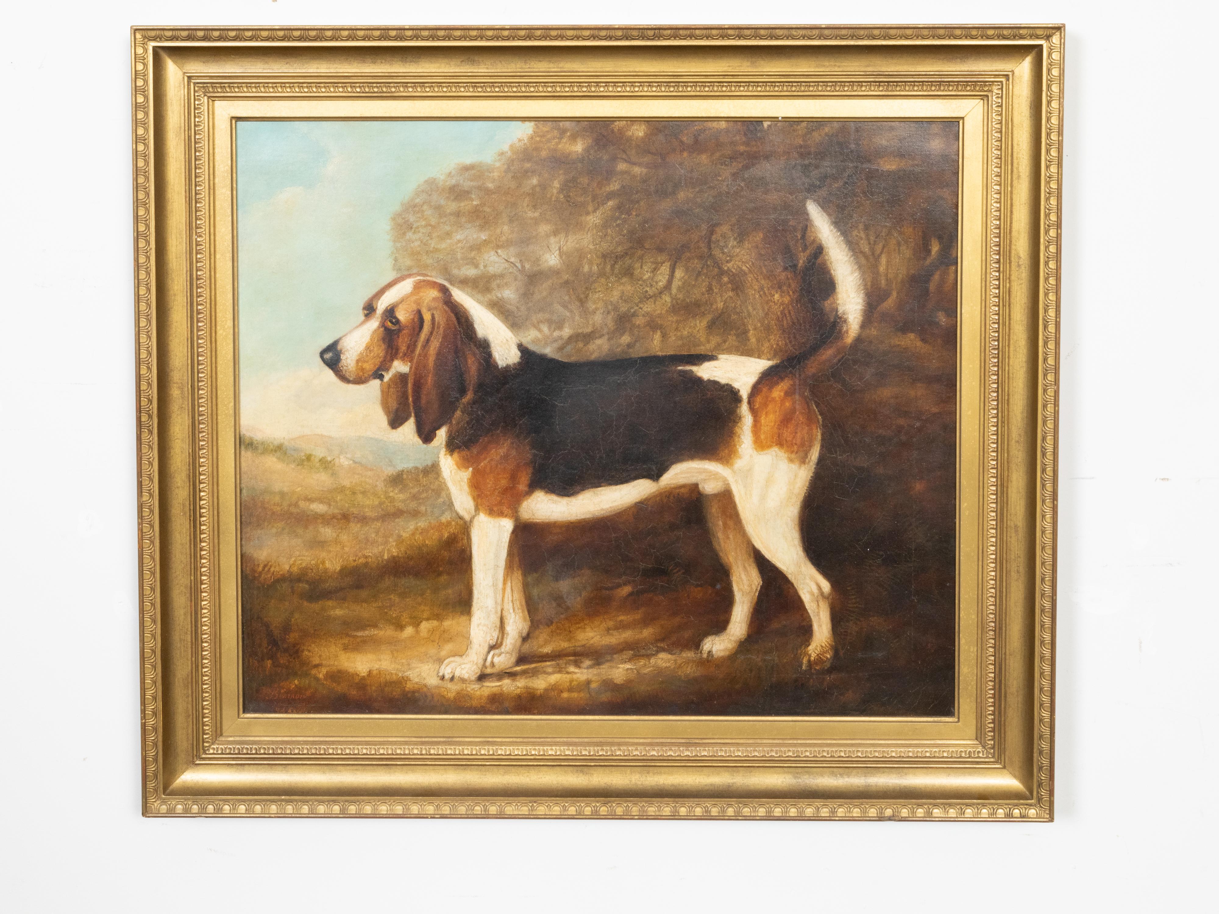 An English oil on canvas horizontal painting from the mid 19th century, signed and dated, depicting a stationary bloodhound hunting dog, in carved giltwood frame. Created in England during the third quarter of the 19th century, this oil on canvas