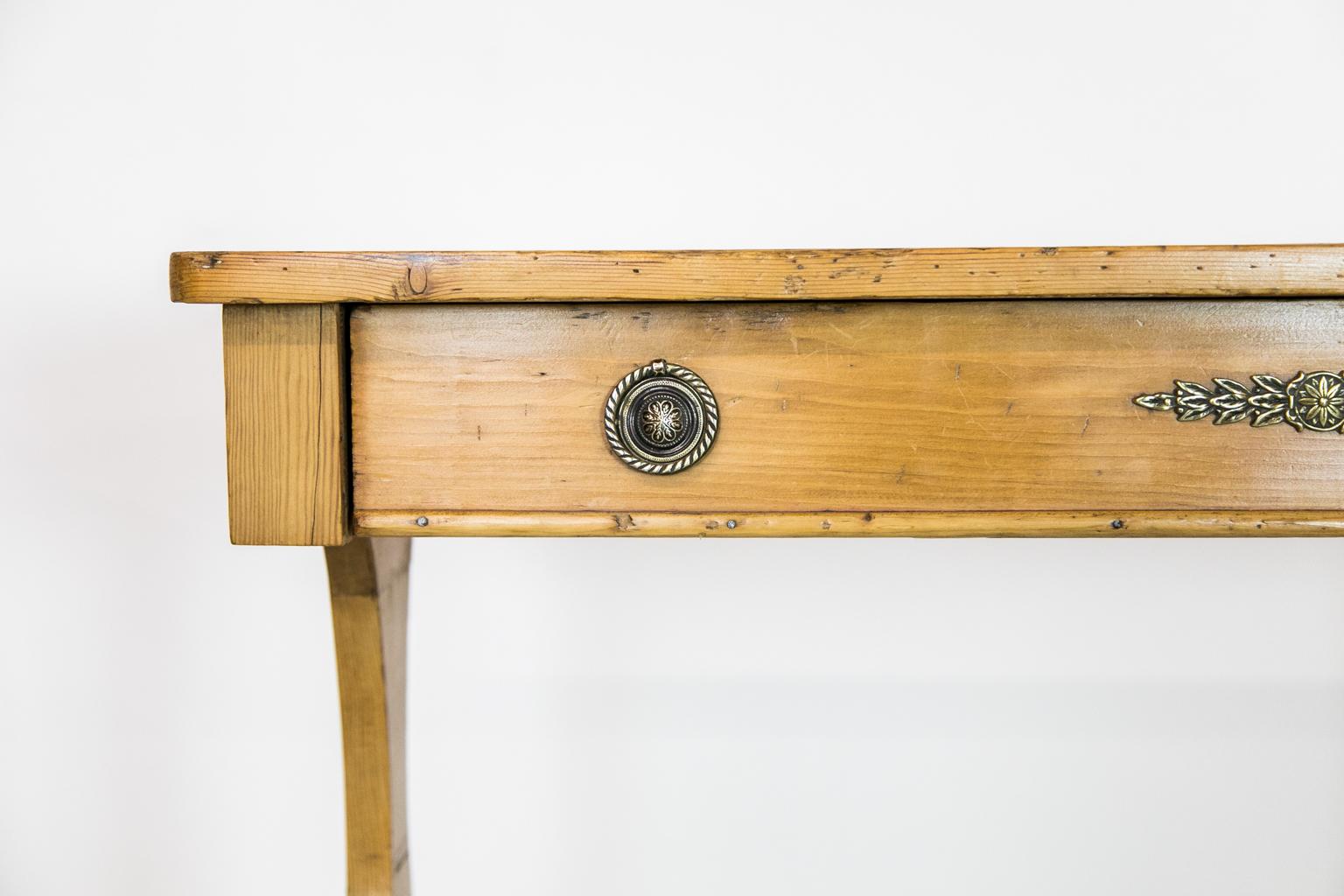 The top of this stretcher table has a weathered patina and a 4 1/2-inch circular mark on the left-hand side. The drawer has an applied bullnose molding on the front of the bottom. The top is supported by a stylize trestle base supported by a turn