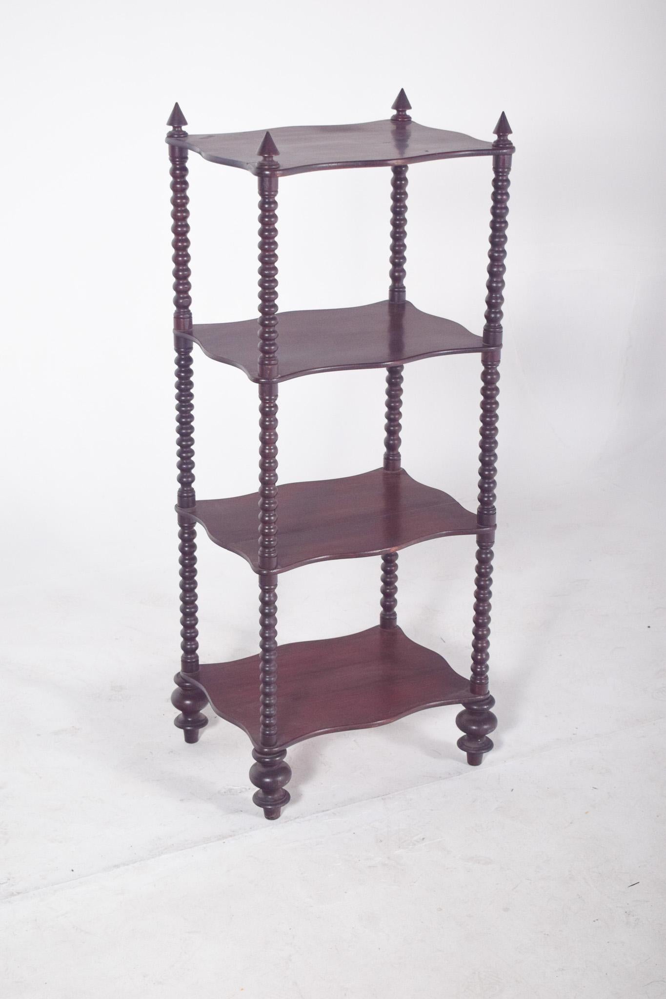 Open bookcase with turned columns.  Veneered in wood, with four shelves with wavy edges and turned side columns, the top finished with decorative pinnacles at the four corners, adding a decorative touch to the furniture. The vertical columns repeat