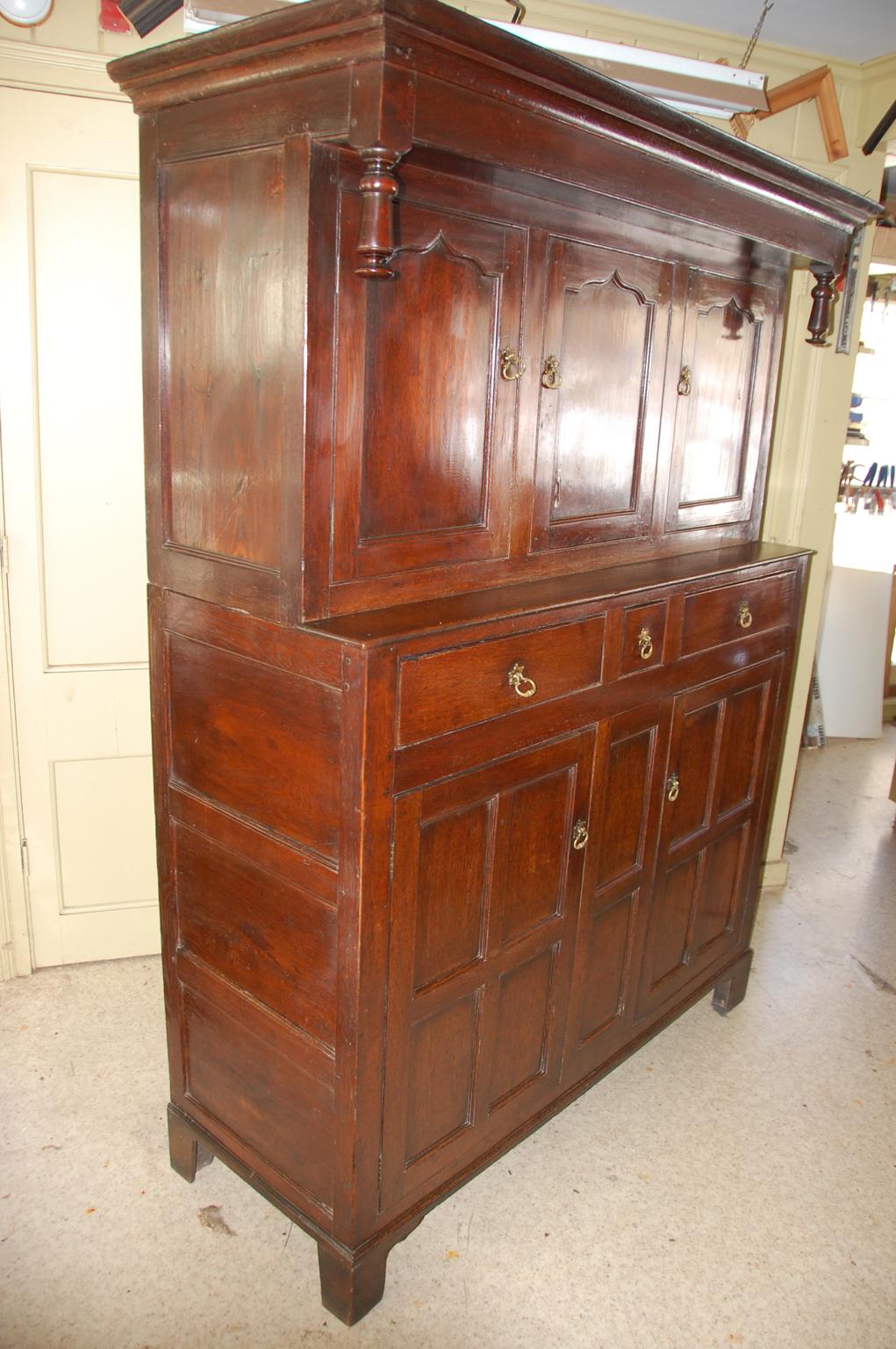 English or Welsh Georgian oak paneled press cupboard with three drawers and five cupboard doors. Behind the cupboard doors are two shelves for storage. The press cupboard was to quote Victor Chinnery 