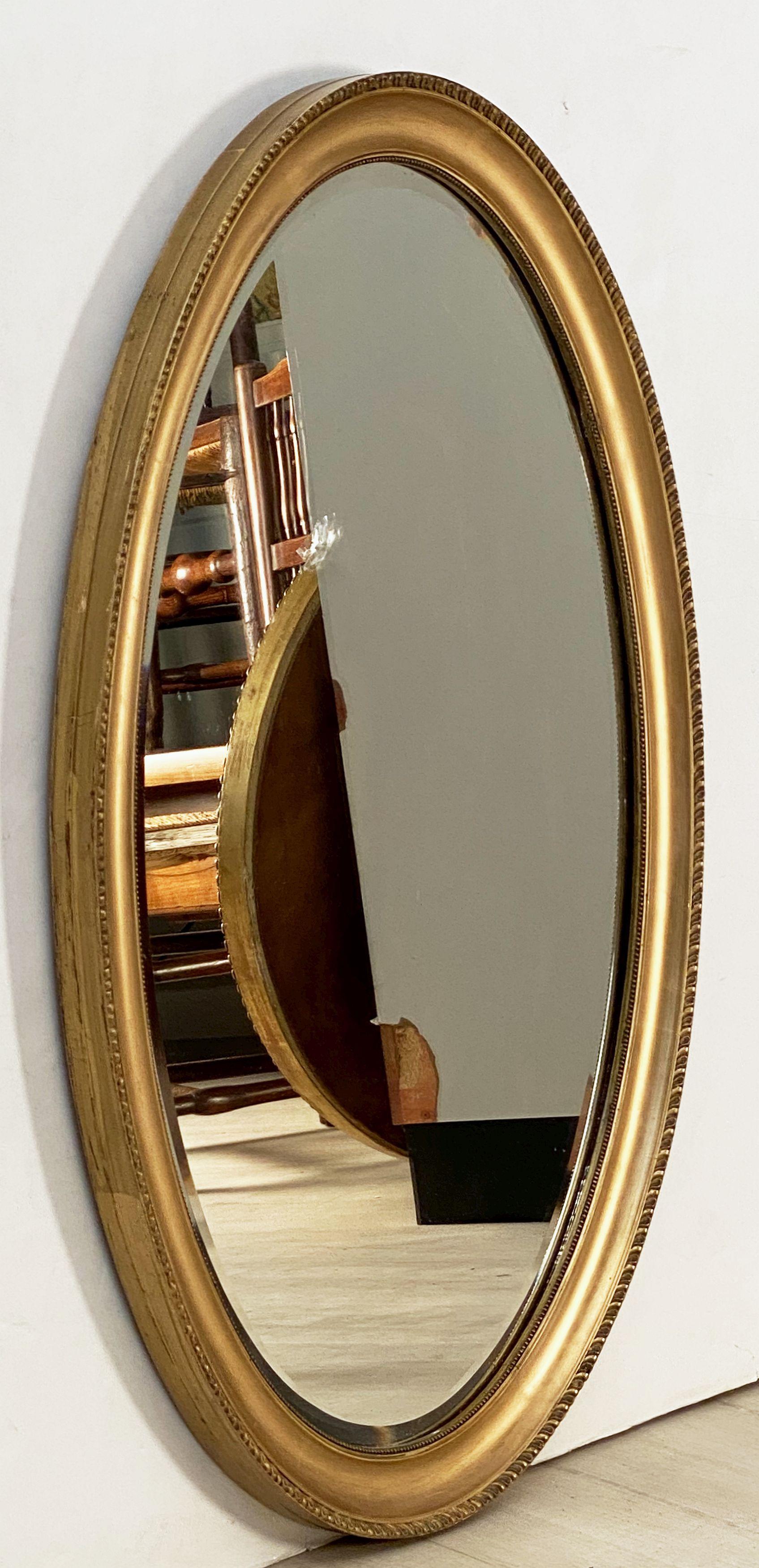 A fine English oval mirror featuring a gilt frame with a decorative gadroon edge surrounding the beveled mirror plate.

Dimensions are H 33 1/2 inches x W 23 3/4 inches.