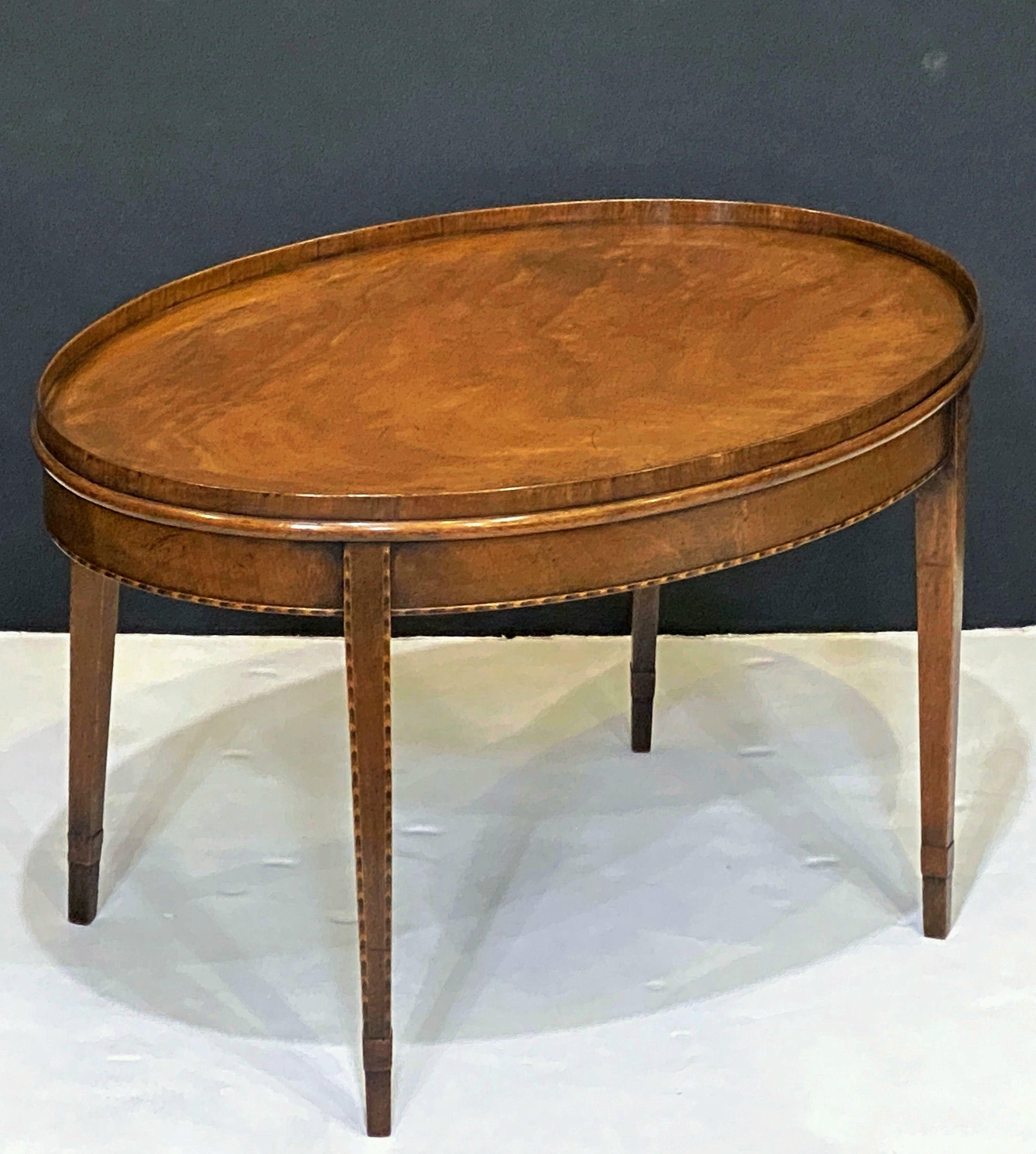 Table basse ou table basse d'appoint anglaise en acajou, présentant un plateau ovale avec des côtés légèrement surélevés en forme de plateau, avec une incrustation décorative dans le rond, reposant sur des pieds effilés à motif de chevrons.