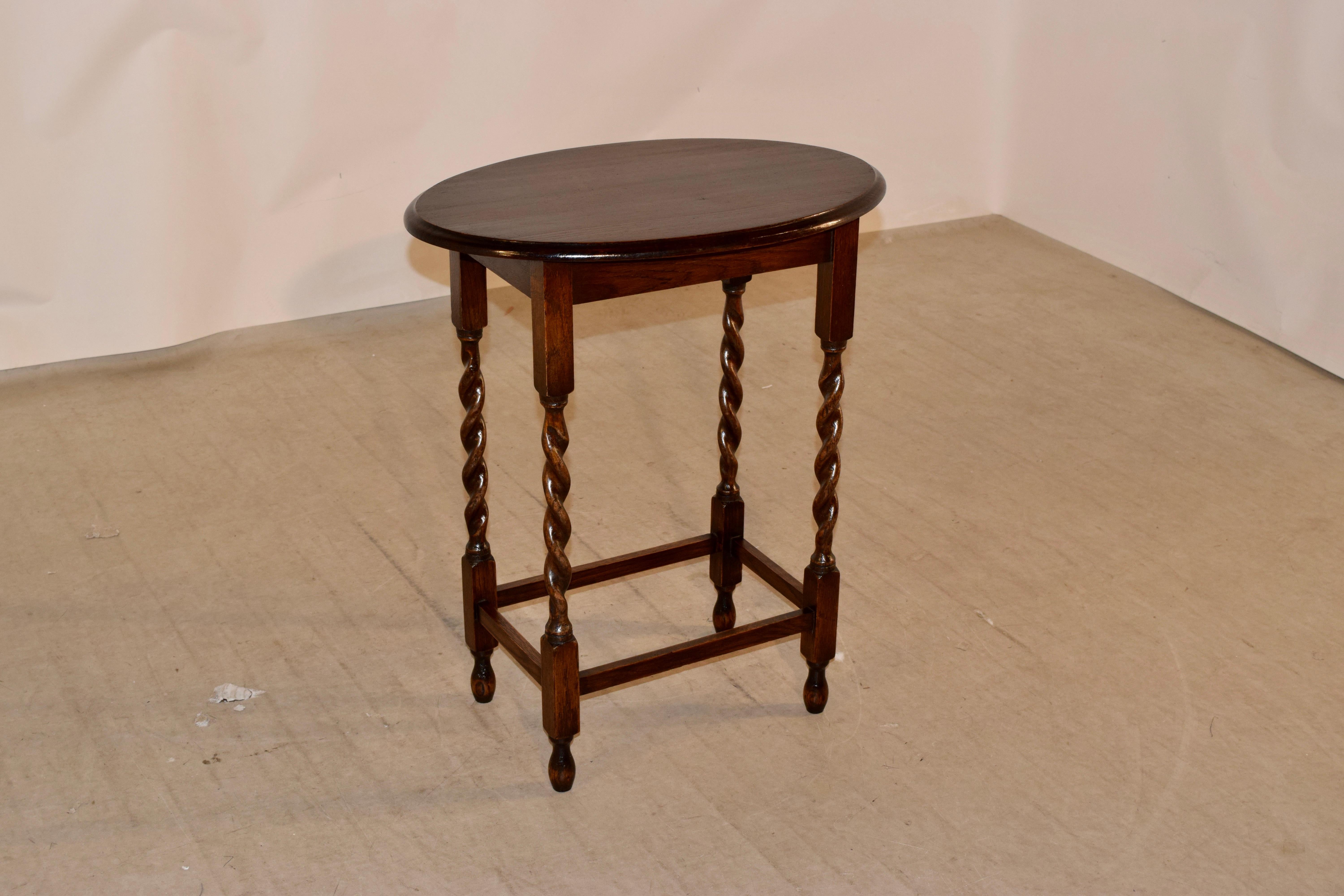 English oak side table with an oval shaped top which has a beveled edge, circa 1900. The apron is simple and is supported on hand turned barley twist legs, joined by simple stretchers and raised on hand turned feet.