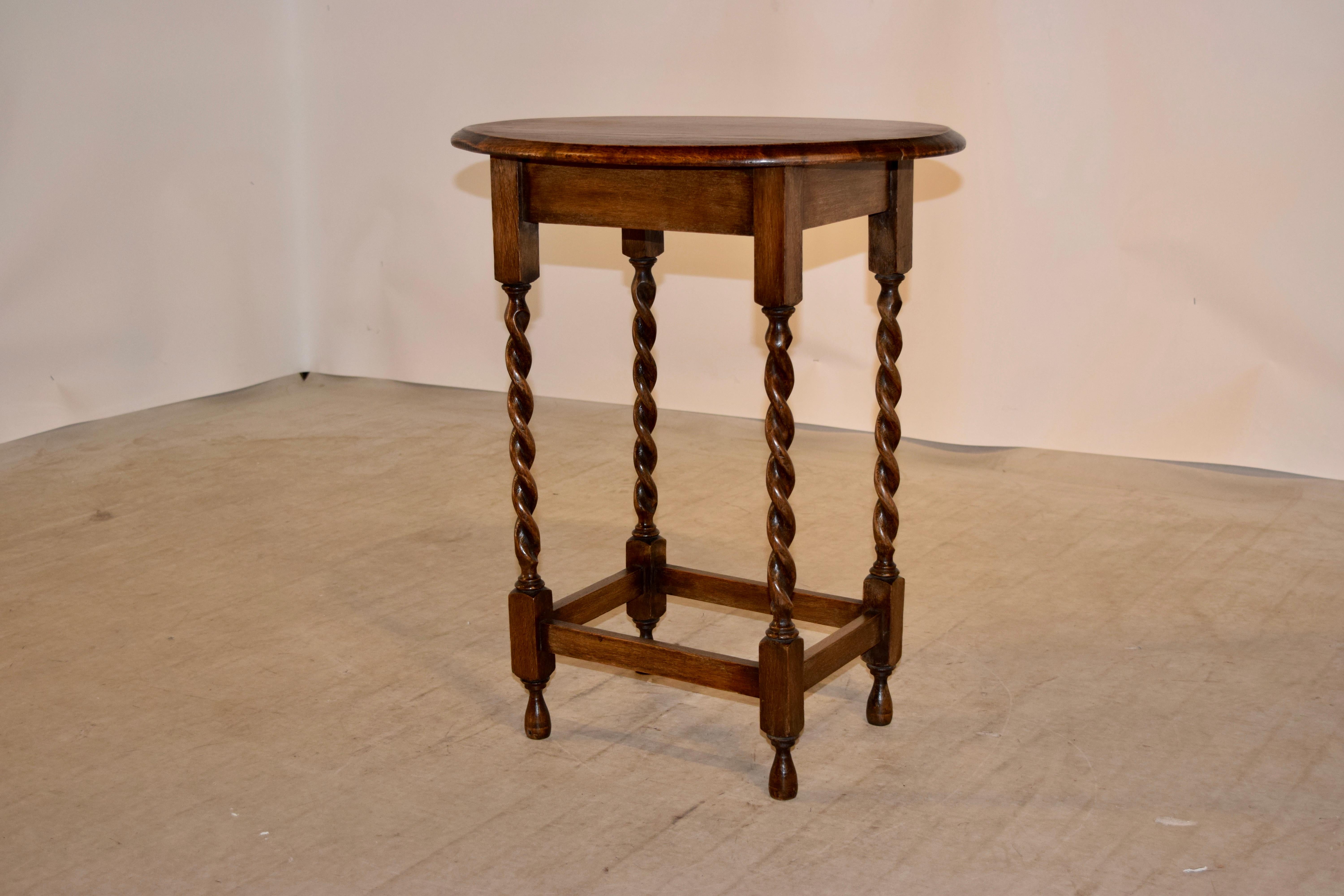 English oak side table with an oval shaped top, which has a beveled edge and follows down to a simple apron and is supported on hand-turned barley twist legs, joined by simple stretchers and raised on hand-turned feet.