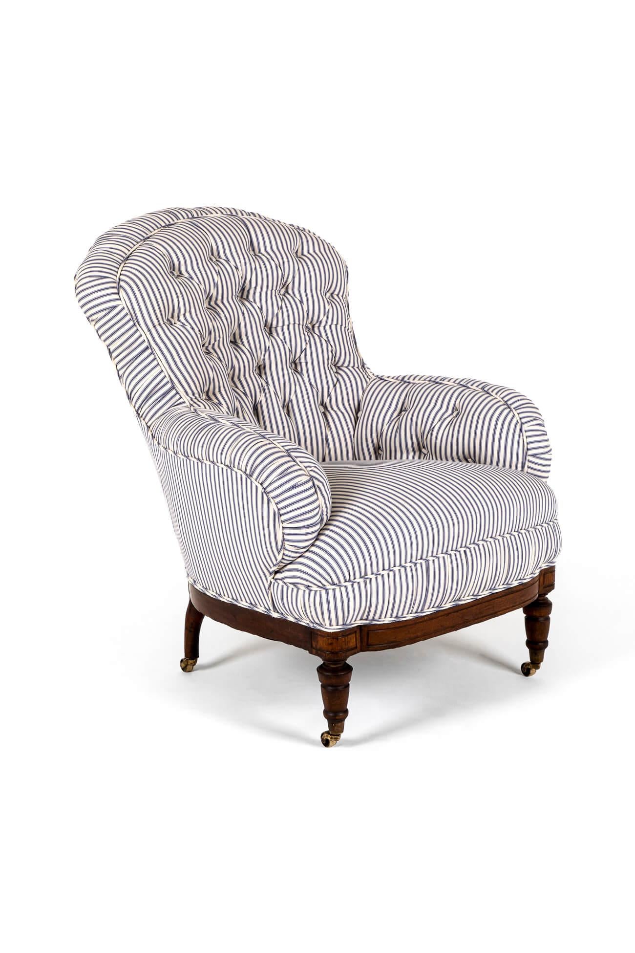 A wonderful Victorian overstuffed button back armchair in blue stripe Cotswold Ticking.

The armchair of generous proportions has a heavy oak frame, raised on turned mahogany legs and finished on brass castors.

The armchair has been fully restored