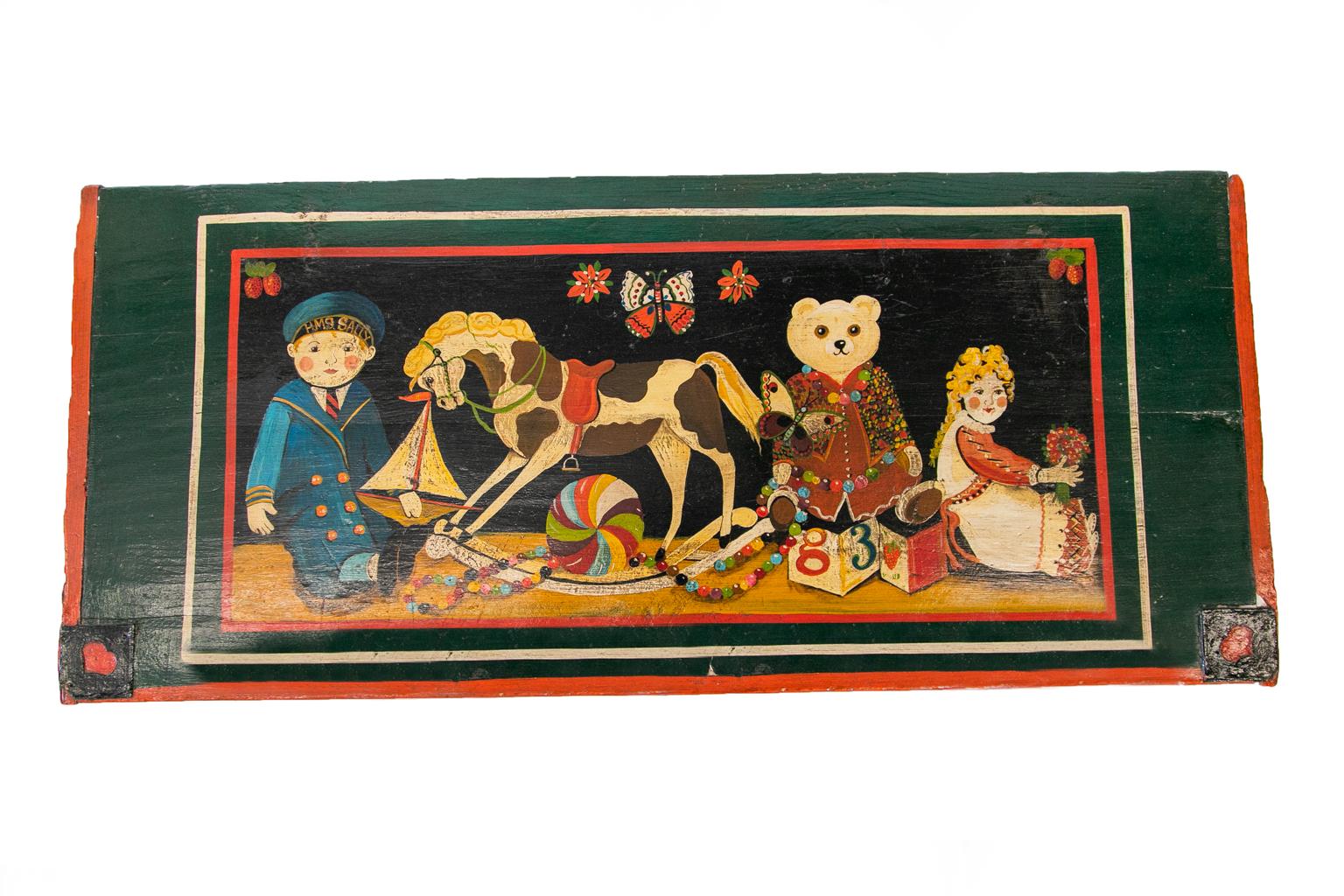 English Painted Blanket/Toy Chest has the original steel decorative straps and carrying handles. The scene depicts children with teddy bears, rocking horses, butterflies, and strawberry hearts in the corners.