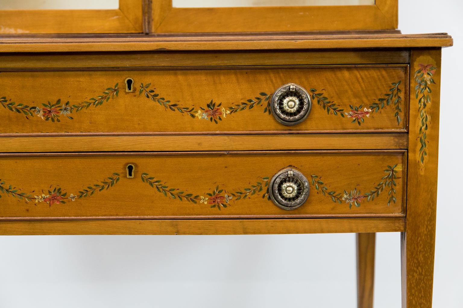 English painted satinwood display case is painted with floral leaf and ribbon motifs.
 