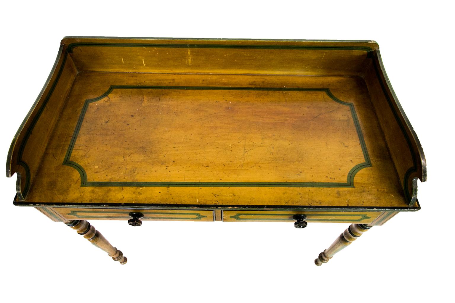 The top of this English painted serving table is mustard color with green and black bindings simulating ebony inlay on the tops, drawer fronts, legs, and sides. The drawer has the original carved octagonal wooden knobs. The top surface has markings