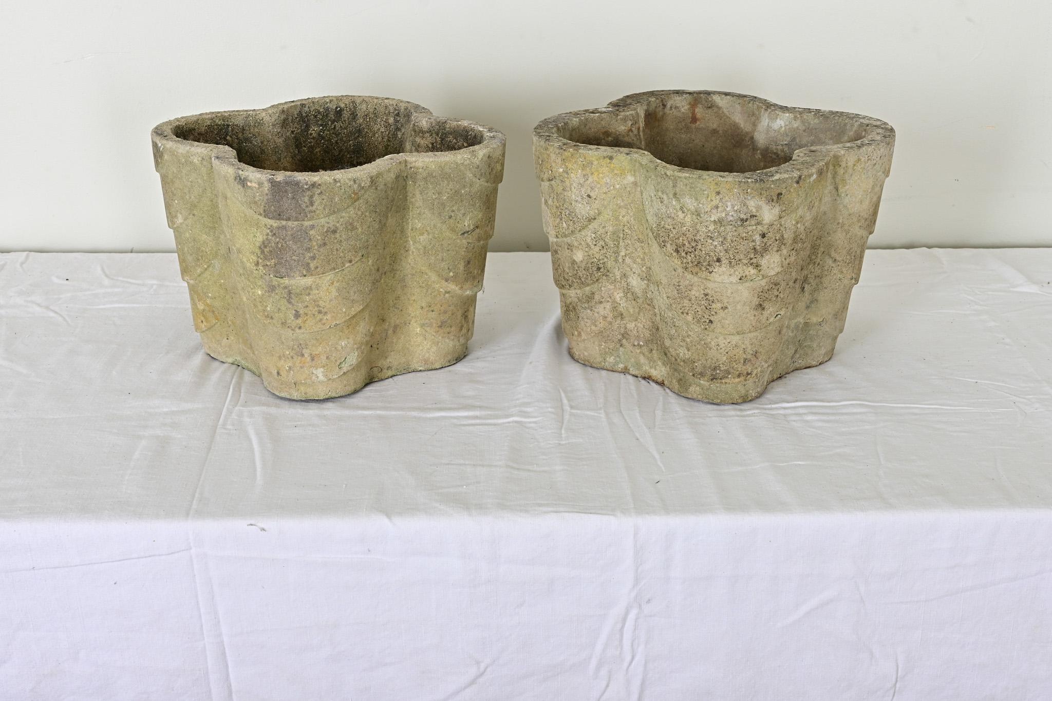 Fabulous pair of English quatrefoil planters from the Art Deco period. The light color, reconstituted stone is greige with patina from time and use. The bases are pierced with a drainage hole for your convenience, and they would be an elegant