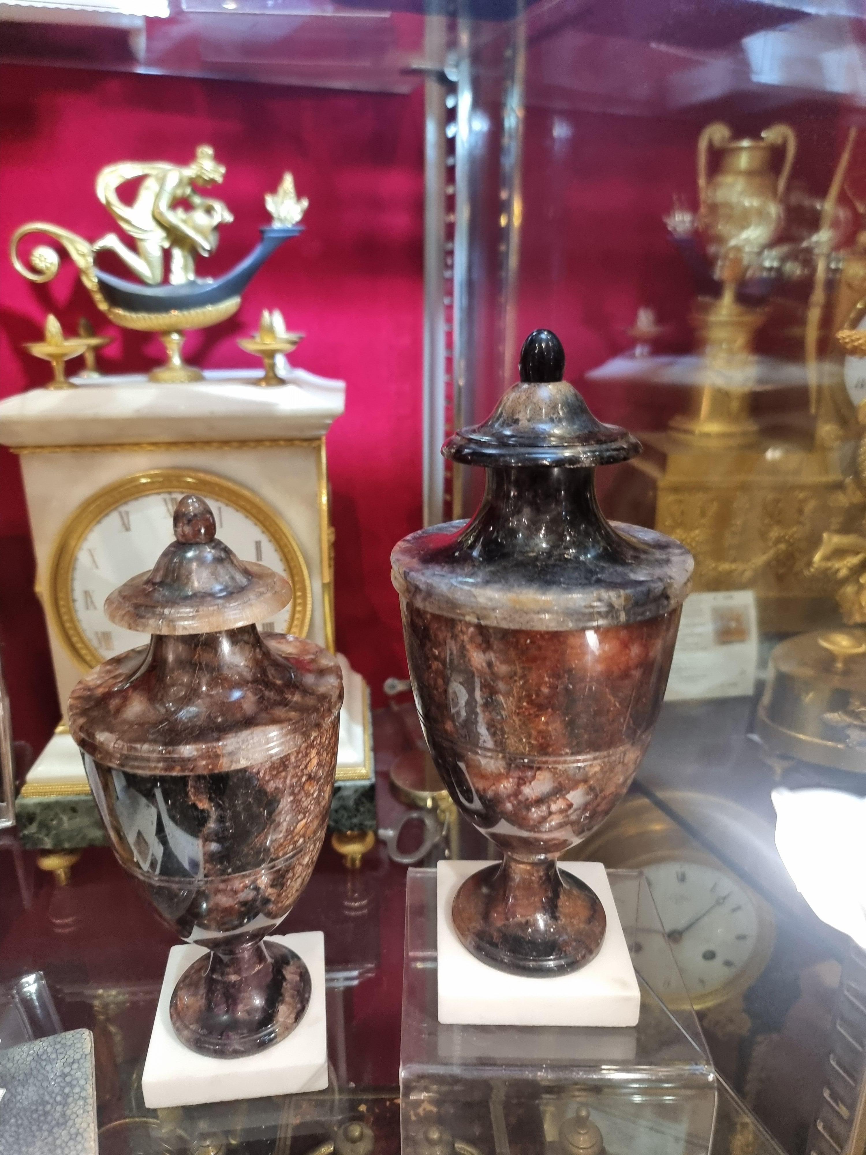 Coppia di urne da guarnitura in fluorite inglesi del XIX secolo, con coperchi fissi a vita e terminali a bottone ogivale, su piedistalli circolari e basi quadrate poco profonde in marmo bianco.