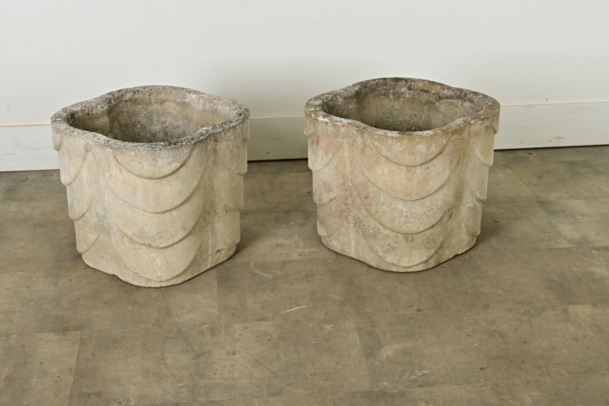 Fabulous pair of English garden planters from the Art Deco period in quatrefoil shape with tactile, scalloped texture draping the exterior. The light color, reconstituted stone is greige with patina from time and use, with a convenient drainage hole