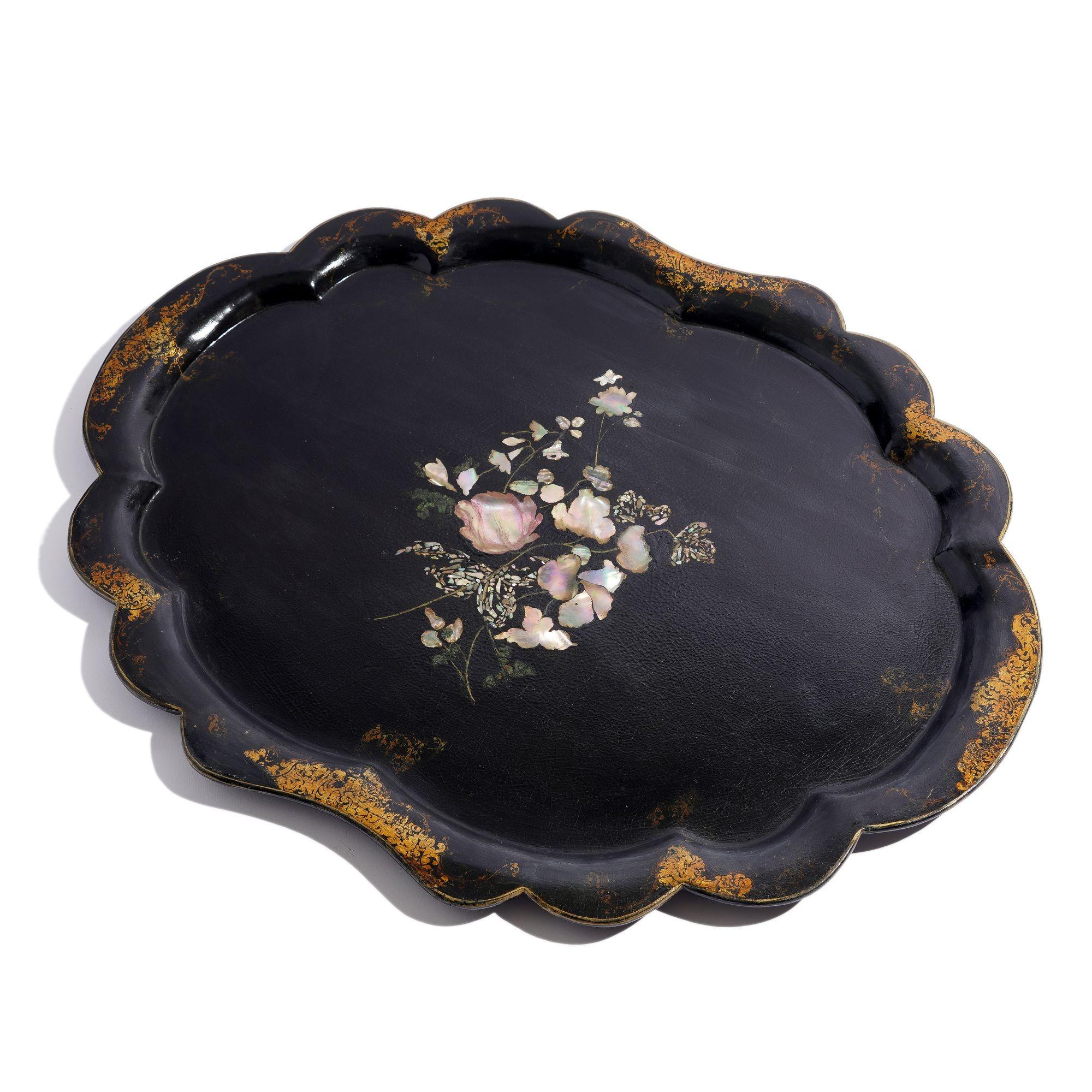 English paper mache tea tray in black with scalloped edge and gilt and bronze powder border in the Rococo taste. The center of the tray is a Mother-of-Pearl inlay incorporated into a botanical decoration.

England, mid 19th century.