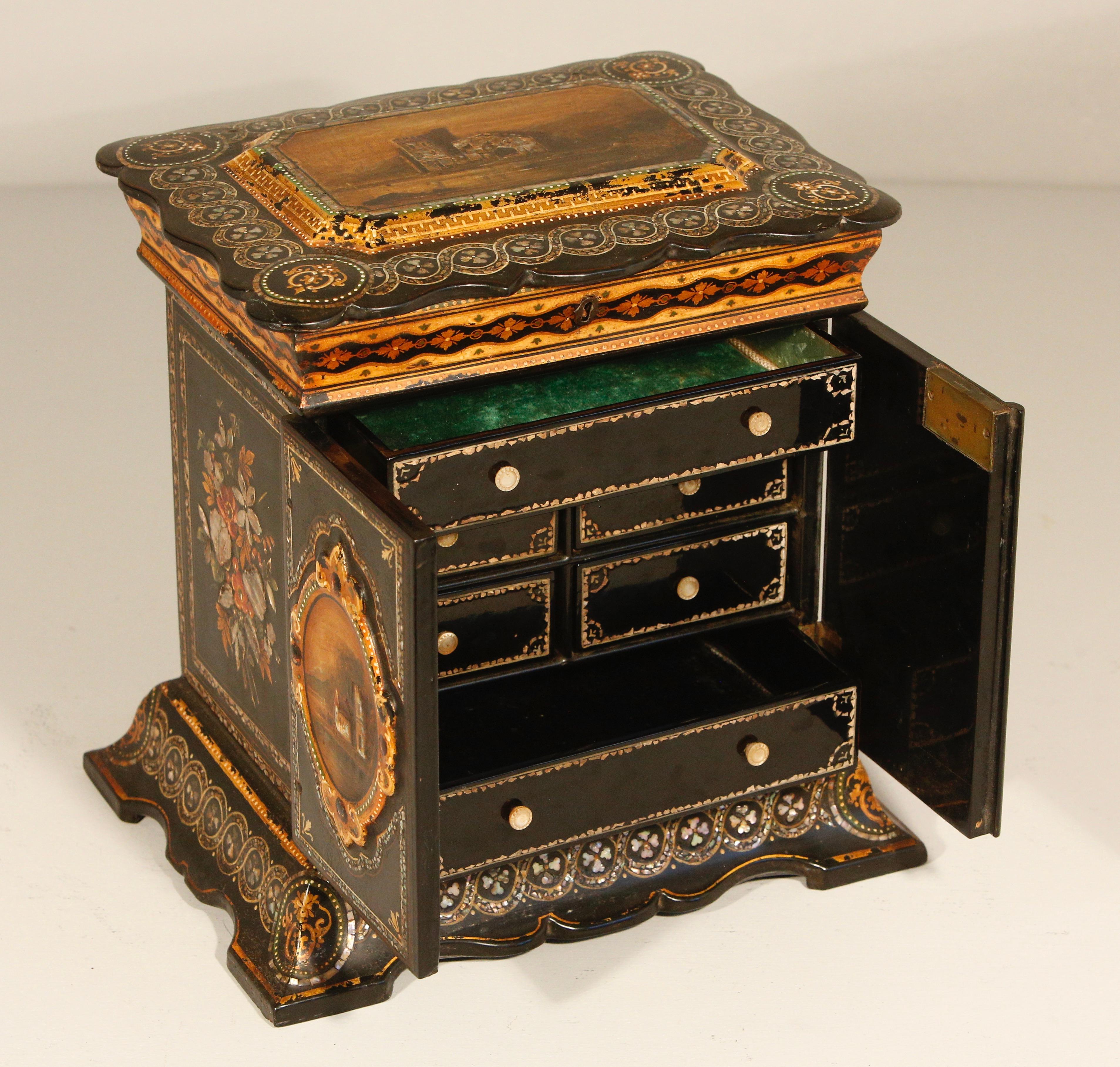 Englische Pappmaché-Schmuck-Nähkabinett-Box CIRCA 1860

Dieser charmante und dekorative Pappmaché-Schrank verfügt über zwei schön gestaltete Vordertüren und sechs Schubladen im Inneren. Die Fronttüren sind mit handgemalten Motiven und Mosaikmuscheln