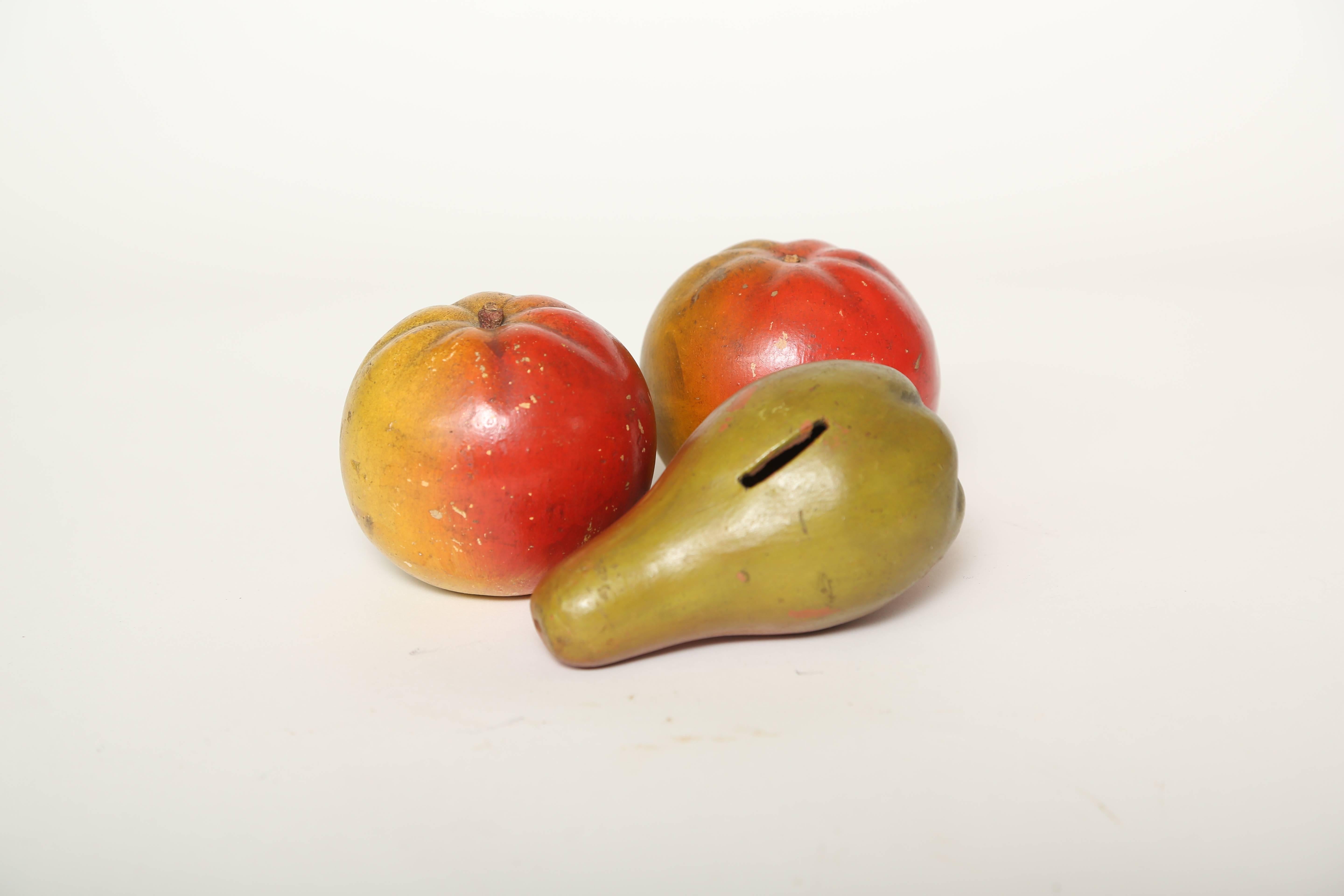 English antique pear and apple pottery fruit. The pear was slotted to be a child's bank, while the two apples were meant for decoration. The red ware pieces were hand-painted in naturalstic colors. Most of these banks were meant for children and