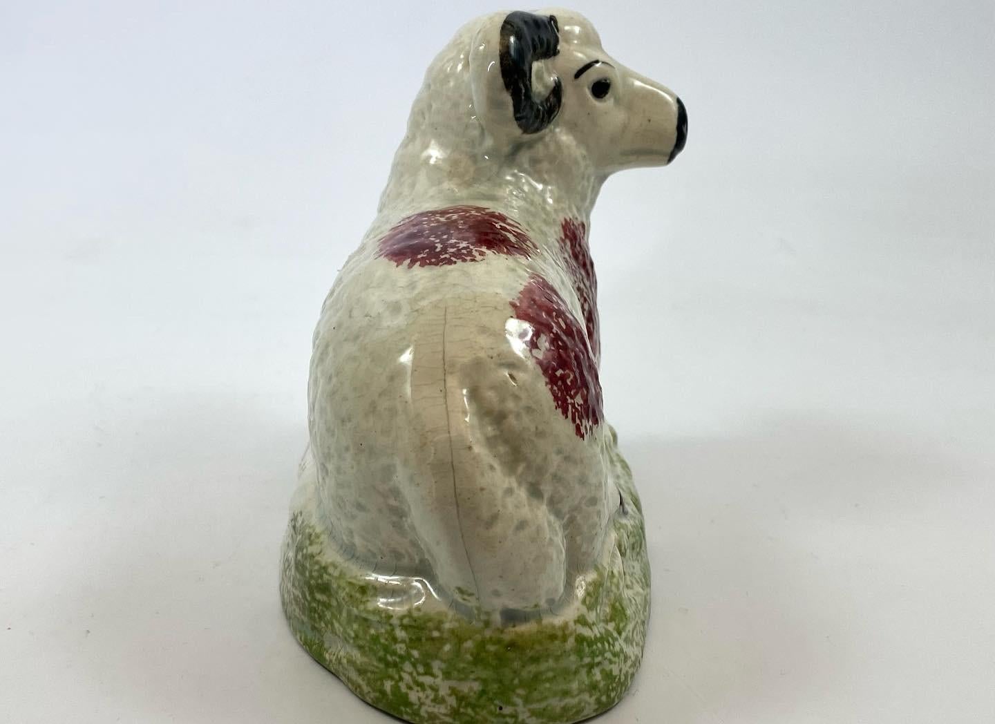 A large English pottery pearlware ram, c. 1830. The recumbent ram, sponged with puce glazed spots, black horns, snout and eyes, upon an oval mound base, sponged in green. All under a pearlware glaze.
North East English, or possibly Scottish