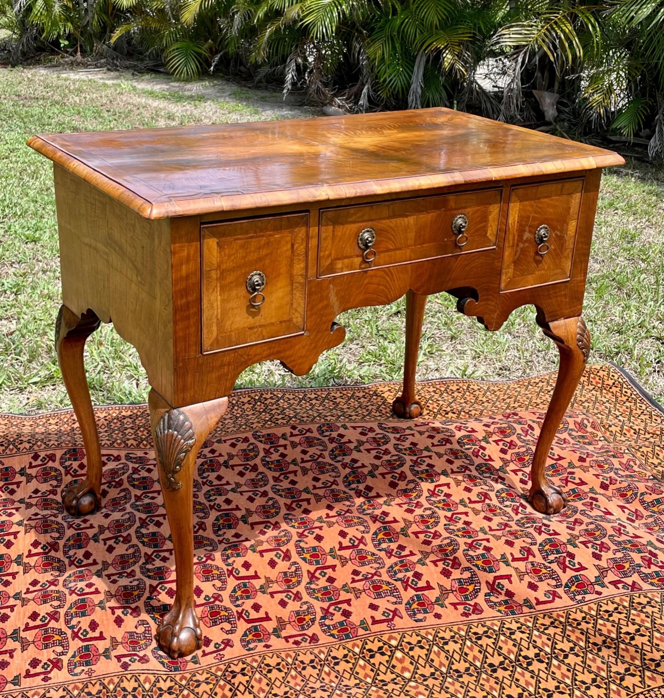 English Period 18th century Queen Anne walnut lowboy.

Refined walnut Lowboy with elegant scalloped apron from the Queen Anne period, about 1740. The molded edge top is quarter veneered with gross banding and with four notched corners. The three