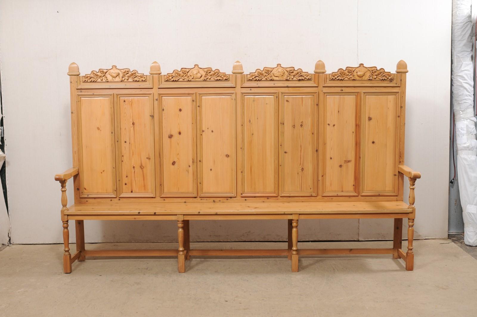 A large-scale English wood-carved hall bench with high back from the mid 20th century. This vintage bench from England is impressively sized at over 10 feet in length and back standing nearly 6 feet tall. The back features eight rectangular panels