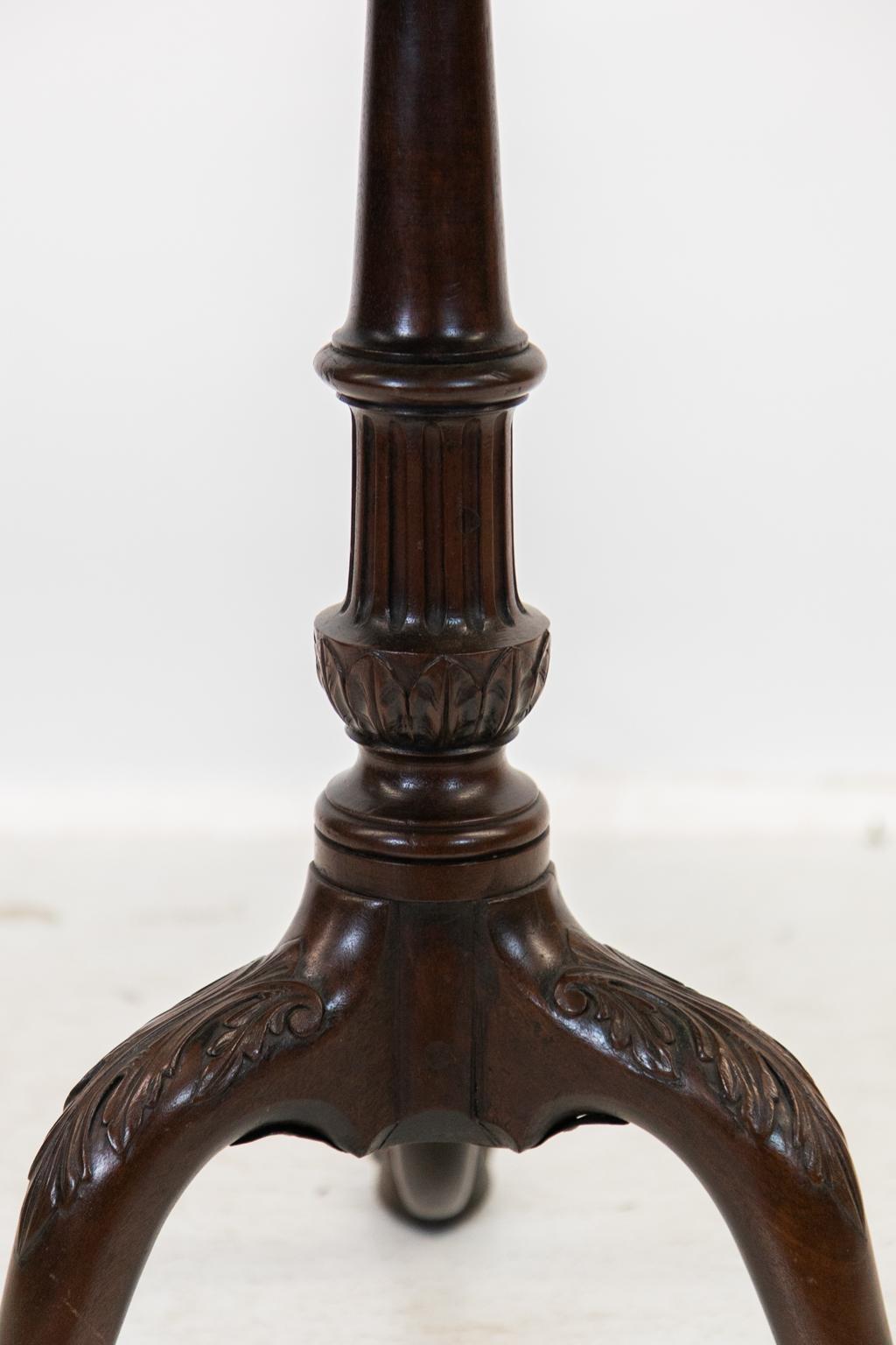 The top of this table has a carved scalloped piecrust edge. There is an old shrinkage crack in the top that has been restored. The turned column has fluting above the leaf carved knop. The legs have acanthus leaf carvings on the knees and terminate