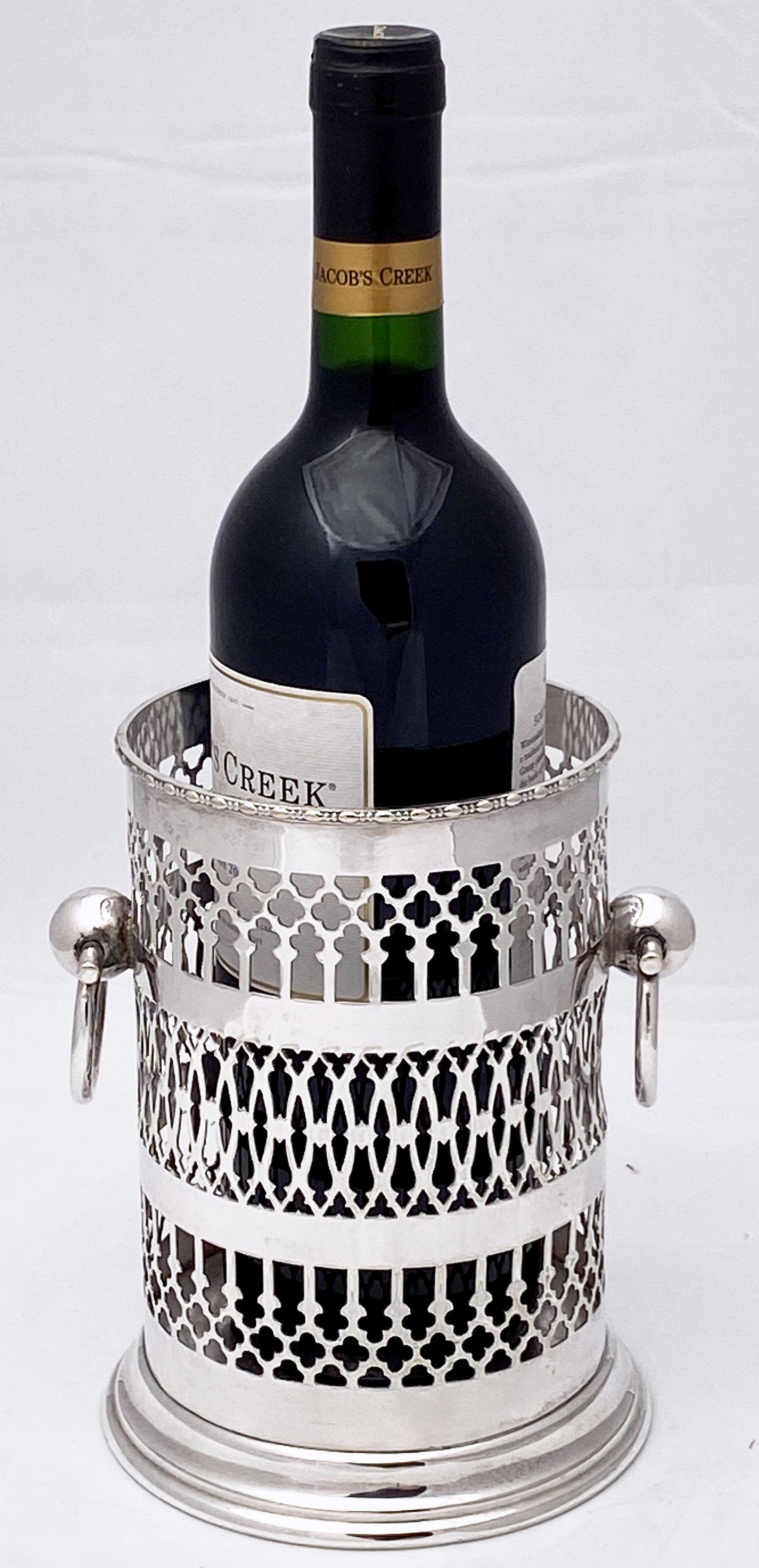 A handsome English wine bottle display holder or coaster of fine plate silver, featuring a rolled edge around the top, with an elegant pierced design around the circumference and opposing ring handles, and raised cylindrical base.

Measure: Rim
