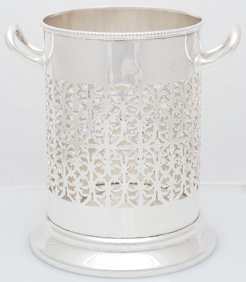 A handsome English wine bottle display holder or coaster of fine plate silver, featuring a rolled edge around the top, with an elegant pierced design around the circumference and opposing handles, and raised cylindrical base.

Measure: Rim Diameter: