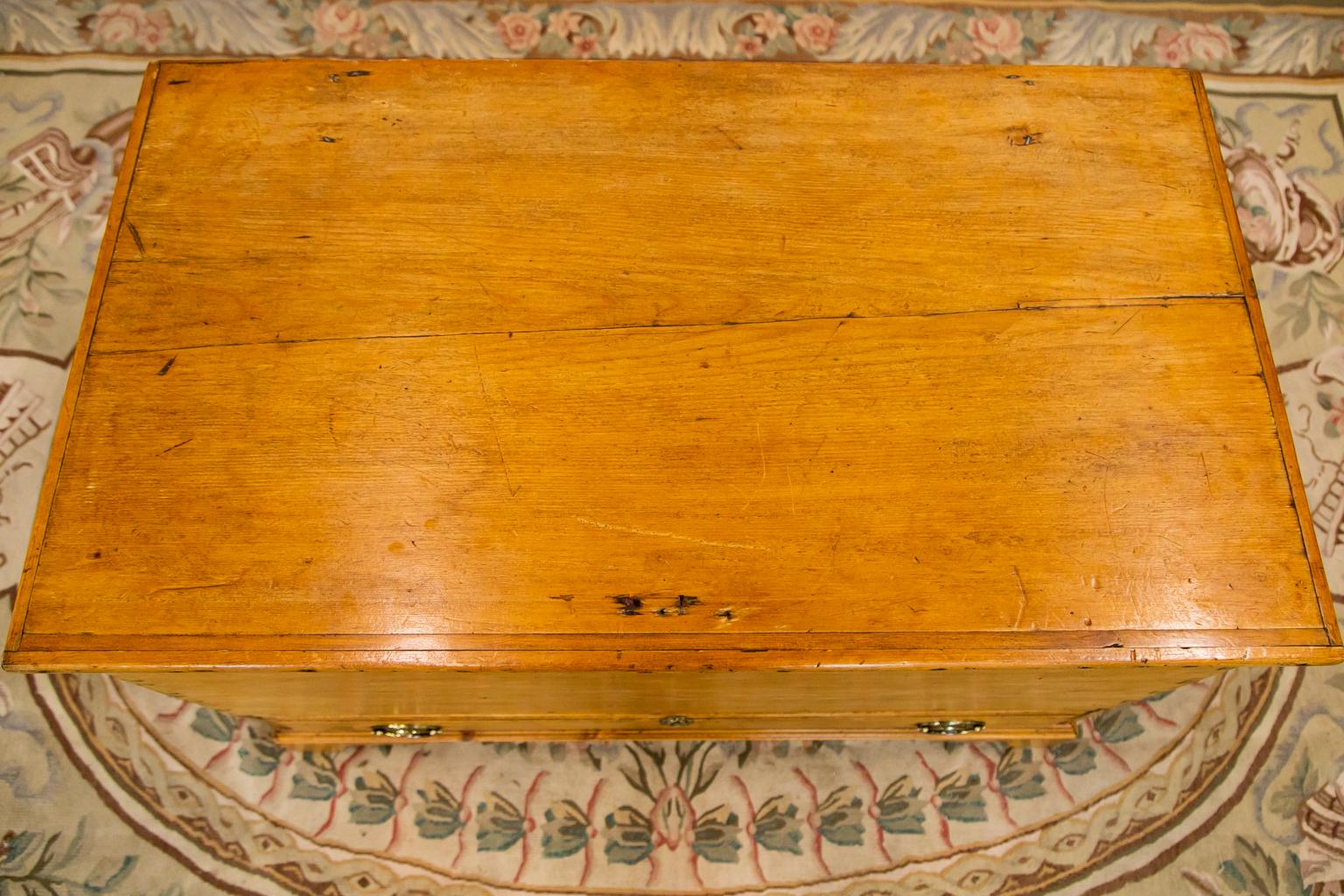 The interior of this blanket chest has the original rat tail hinges and lock. The front has exposed dovetailing. The drawer handles are later. There is a shrinkage separation in the top.