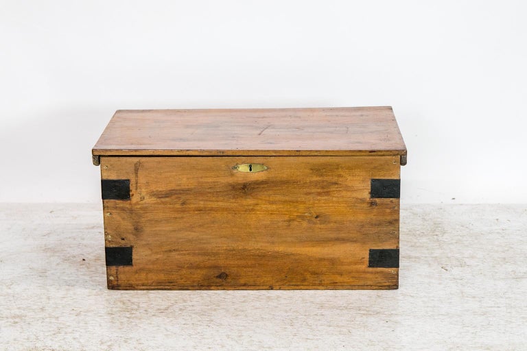 This pine box/blanket chest has the original rattail hinges. It has the original steel strapping, carrying handles, and brass escutcheon.