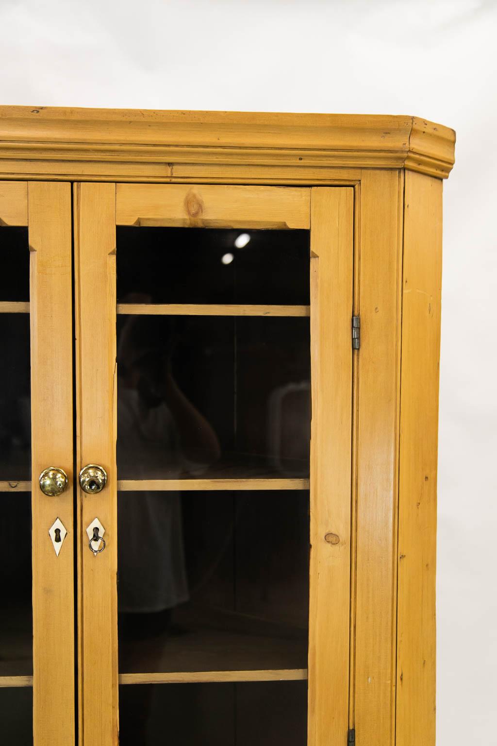 The top of this corner cupboard has two glazed doors which are recessed and framed with chamfered moldings. The lower doors have solid panels with matching chamfered moldings. The center drawer is a working drawer, but the flanking small drawer