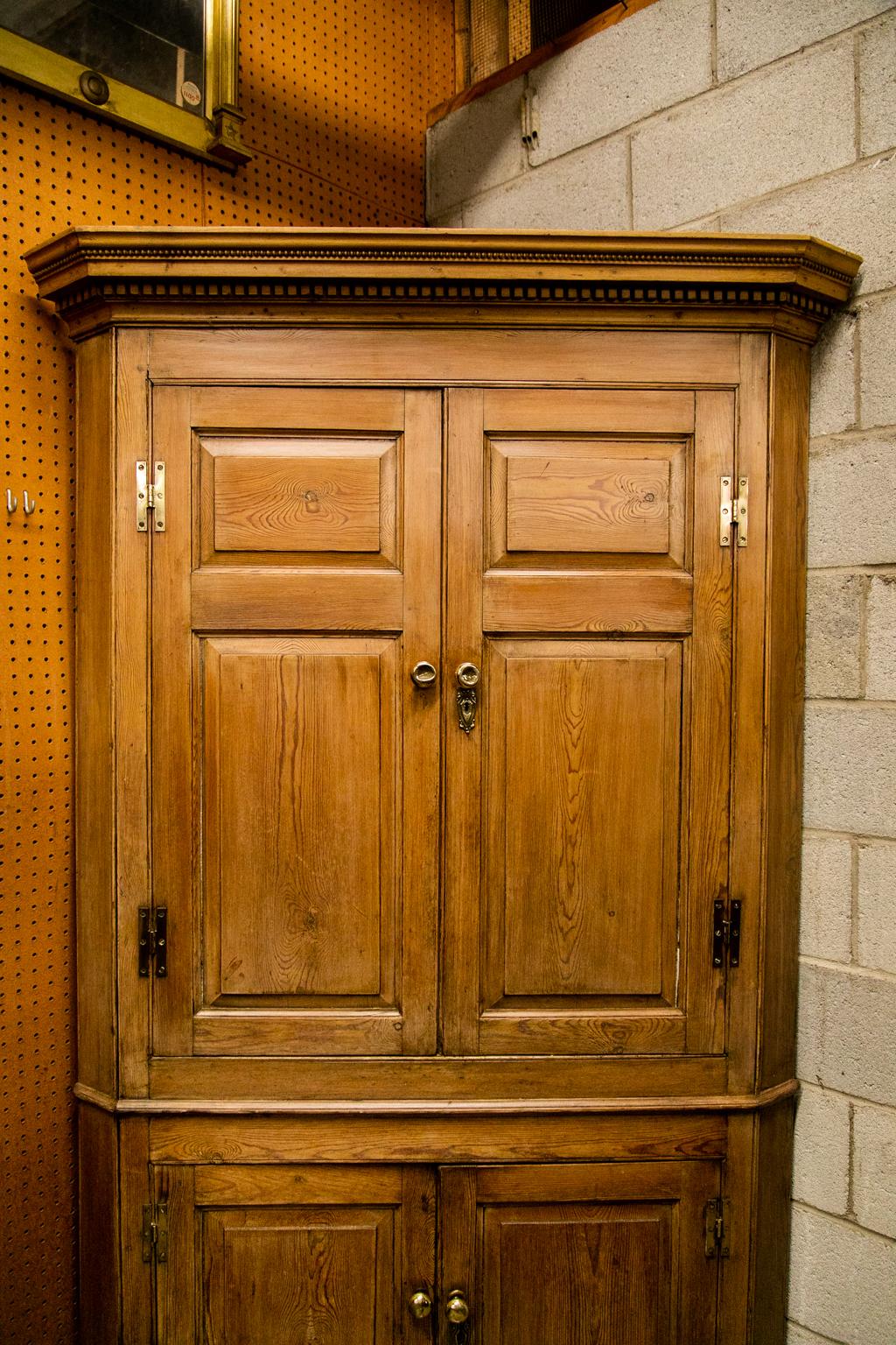 The cornice of this corner cupboard has a dentil and repeating bead molding. The doors on the top and bottom have raised panels framed by shaped moldings. The interior has been painted at a later date.