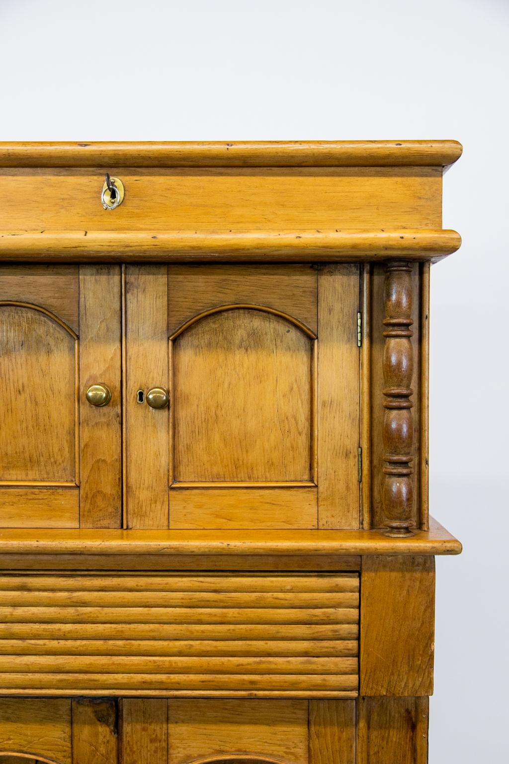 This very unusual English pine cupboard is one of a kind. There is a lift top compartment that is 3 1/2” deep and has its original working lock and key. It has bull nosed moldings on the top section. The top and bottom doors have arched recessed