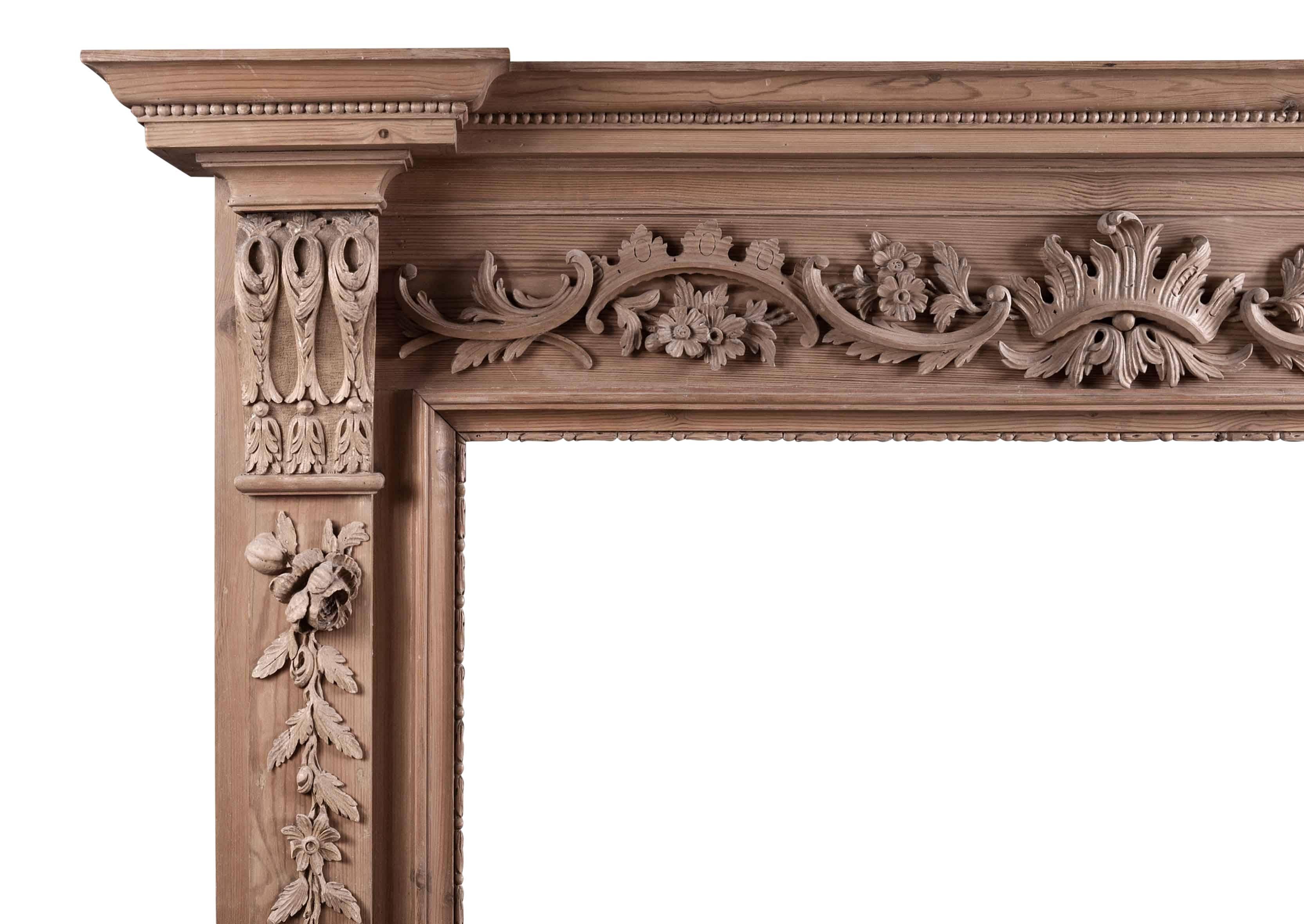 An English carved pine fireplace, the frieze of carved c-scrolls and foliage, the jambs with drops of fruit and leaves, surmounted by carved brackets and breakfront shelf, 20th century.

Measures: 
Shelf Width:	1650 mm      	65 in
Overall