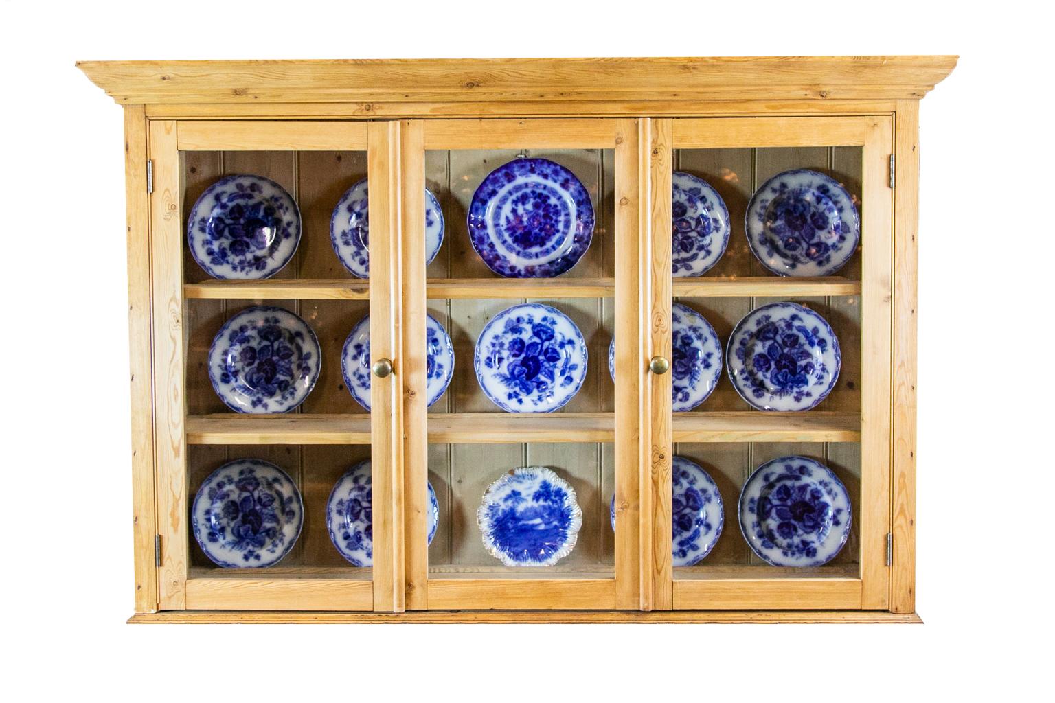 English pine hanging cabinet with glass doors, and a center glass panel with three interior shelves. The top space is 14.5 inches, the middle space is 10.5inches, and the lower space is 12.5 inches. All three have plate strips, which can be removed