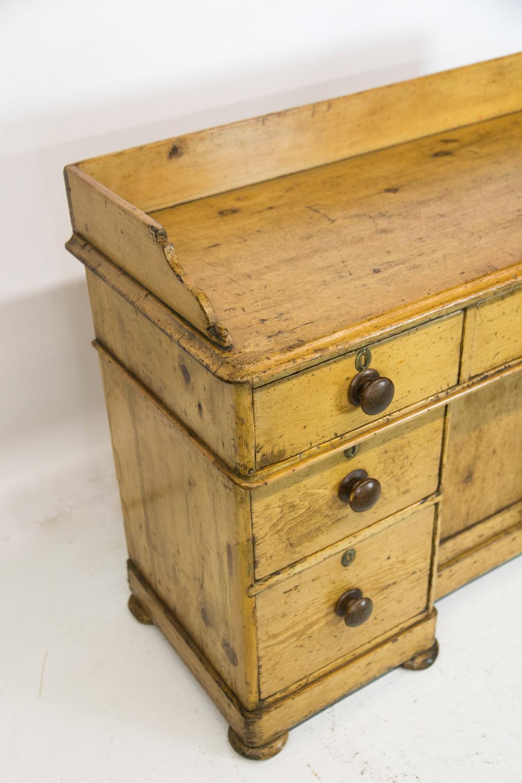 English pine knee hole server, retaining its original fruitwood knobs. The gallery has shaped fronts, and the top has an ogee molded edge. Two lower drawers on each side have a one inch recess from the top. The center cabinet has one interior shelf.