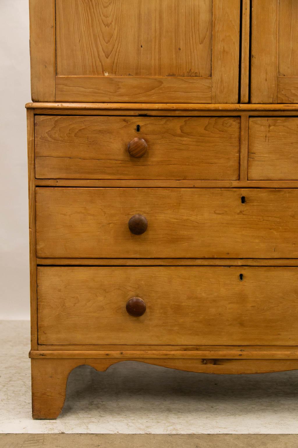The top of this linen press has recessed panel doors which open to expose two fixed shelves in either side. The drawers have original locks and knobs. There are some shrinkage cracks on the sides.