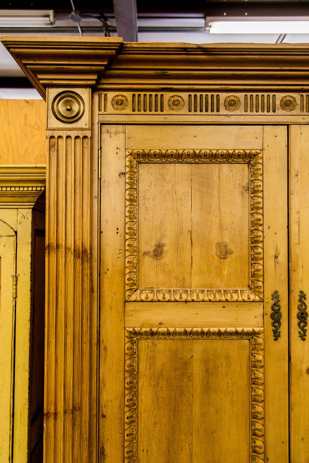 This cupboard is made from antique reclaimed pine. It has carved fluting and rosettes in the frieze and fluting in the stiles of the top and bottom sections. The doors have recessed panels framed with carved moldings. The top interior has one shelf