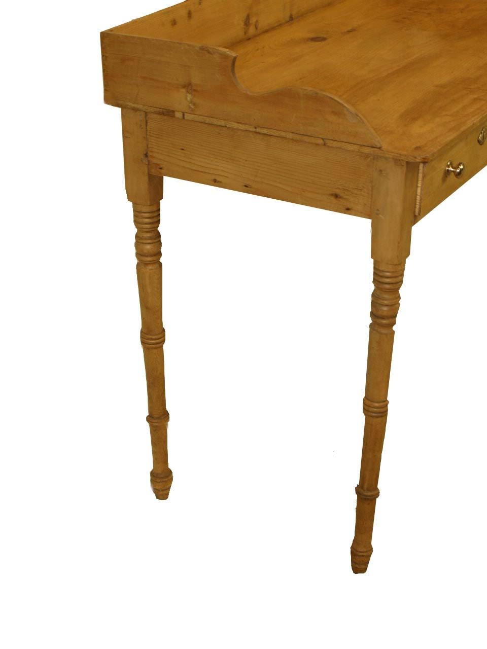English pine serving table with gallery surrounding the top, two drawers with brass ball knobs, delicately turned legs, the top has a slight indention ( see photo of left hand side) , beautiful color and patina. The overall height to the back of the