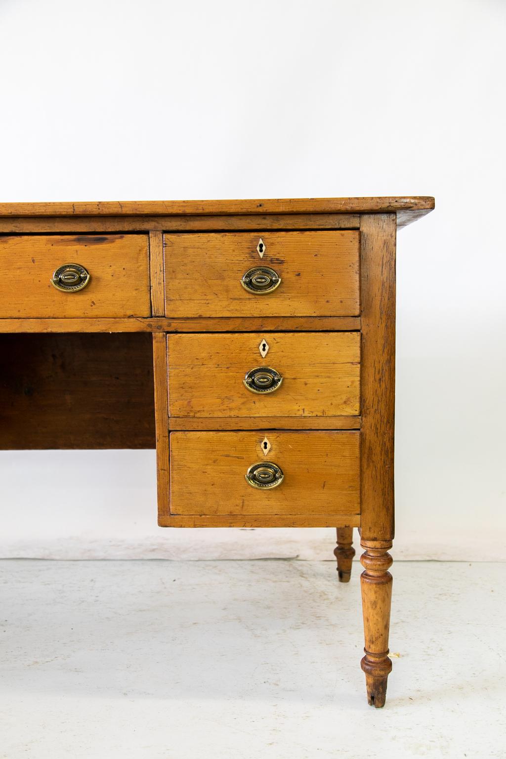 English pine seven-drawer writing desk, with the locks and most of the inlaid diamond bone escutcheons being origin. The top has green leather with gold and blind tooling. The back of the desk is finished, on turned legs.
   