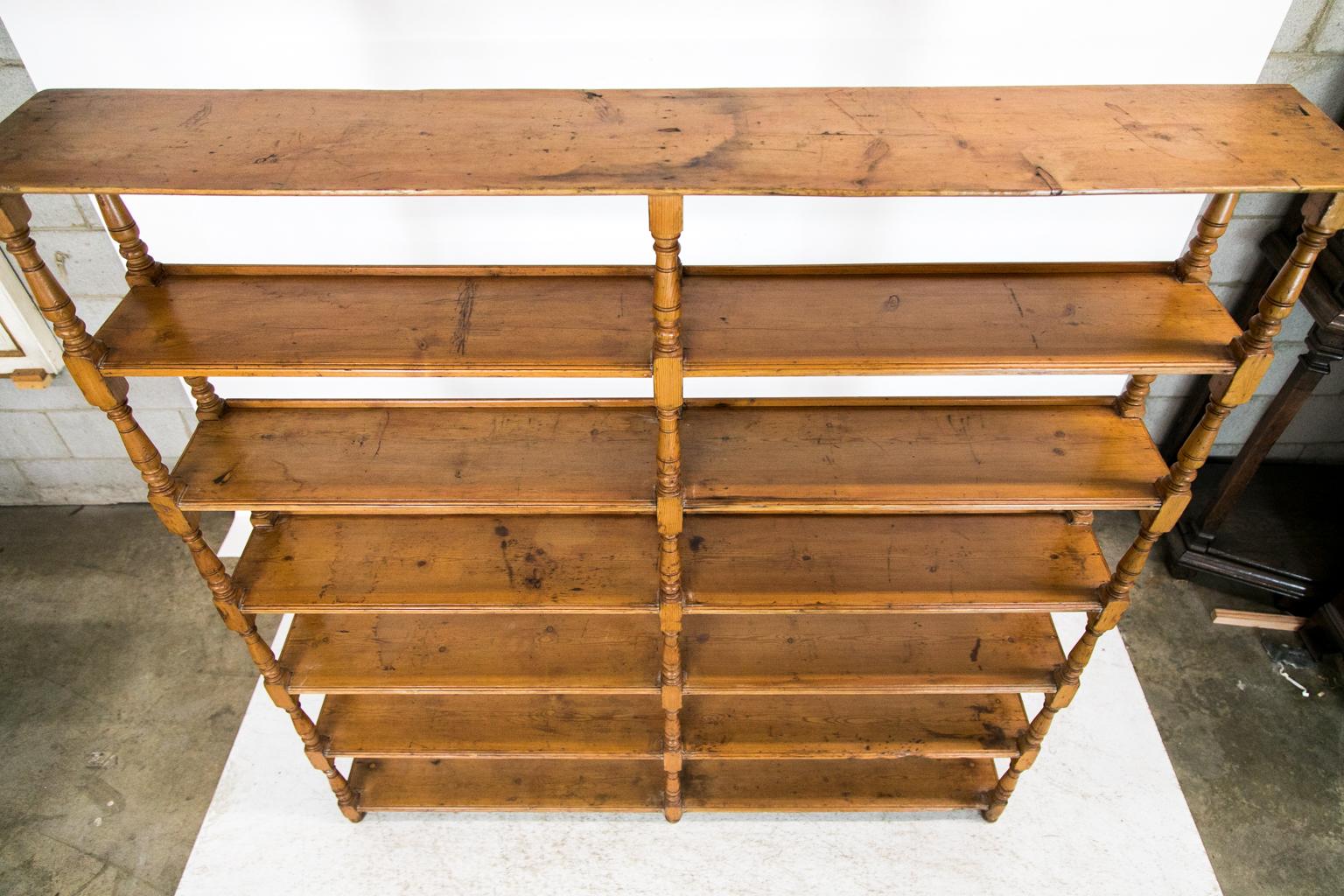 The front shelves of this pine shelf have shaped top edges with a 3/4-inch retaining gallery at the rear. The shelves are supported by six turned supports that are one single length of wood from top to bottom which are on the front and rear.
   