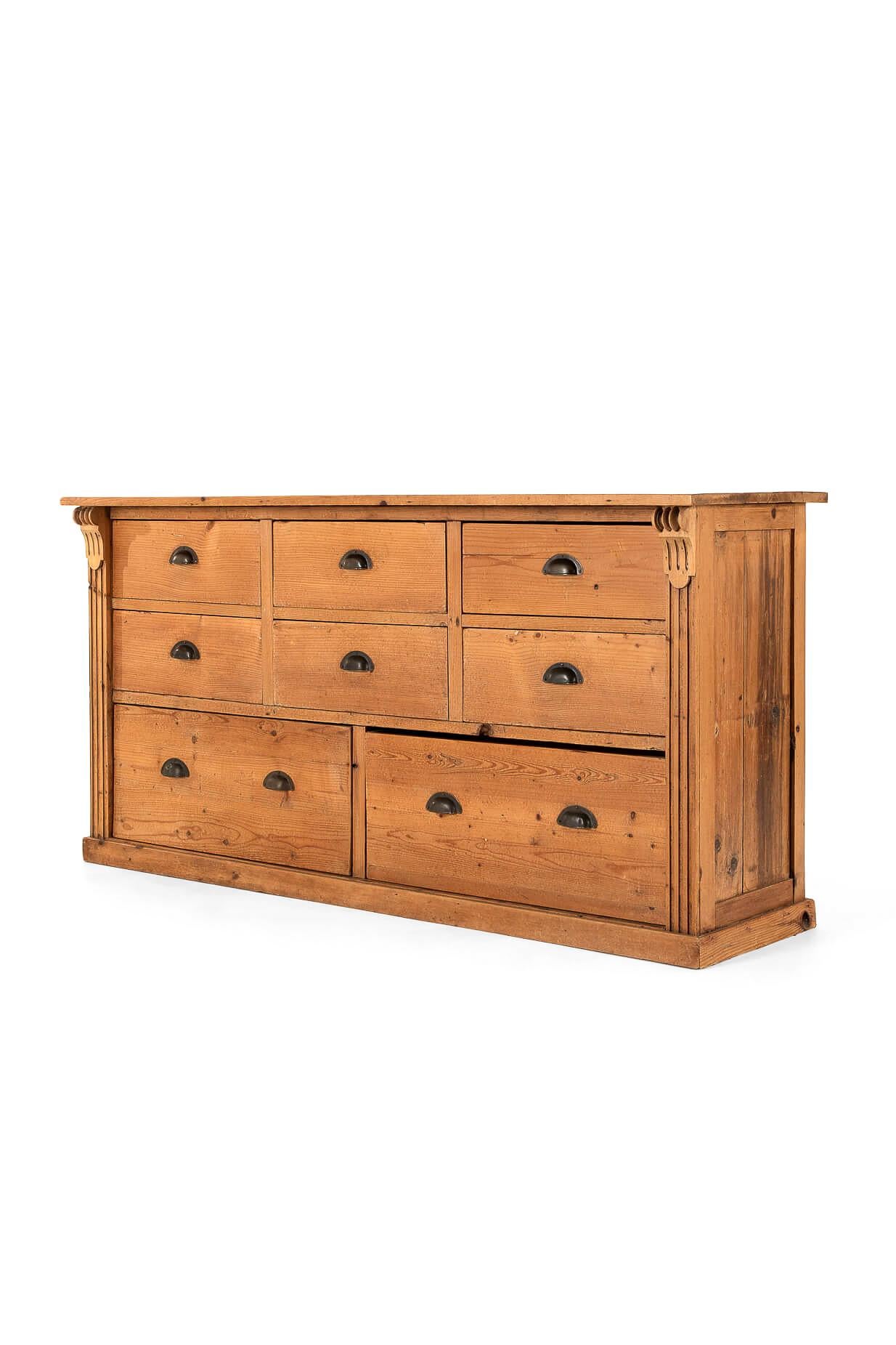 A superb pitch pine shop counter from a tobacconist shop with a substantial plank top.

Each end is flanked by decorative carved corbels, fluted parallel columns and raised on a plinth base.

Six large smooth-running drawers over two larger frieze