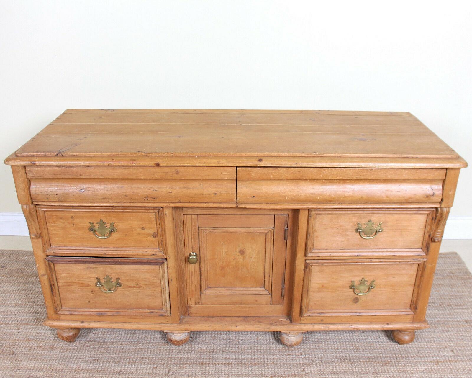 An impressive 19th century pine dresser base.

The top with chamfered edges and fitted two long shaped front drawers to frieze. A central cupboard enclosed storage flanked by drawers mounted with good handles, dovetailed jointing and solid