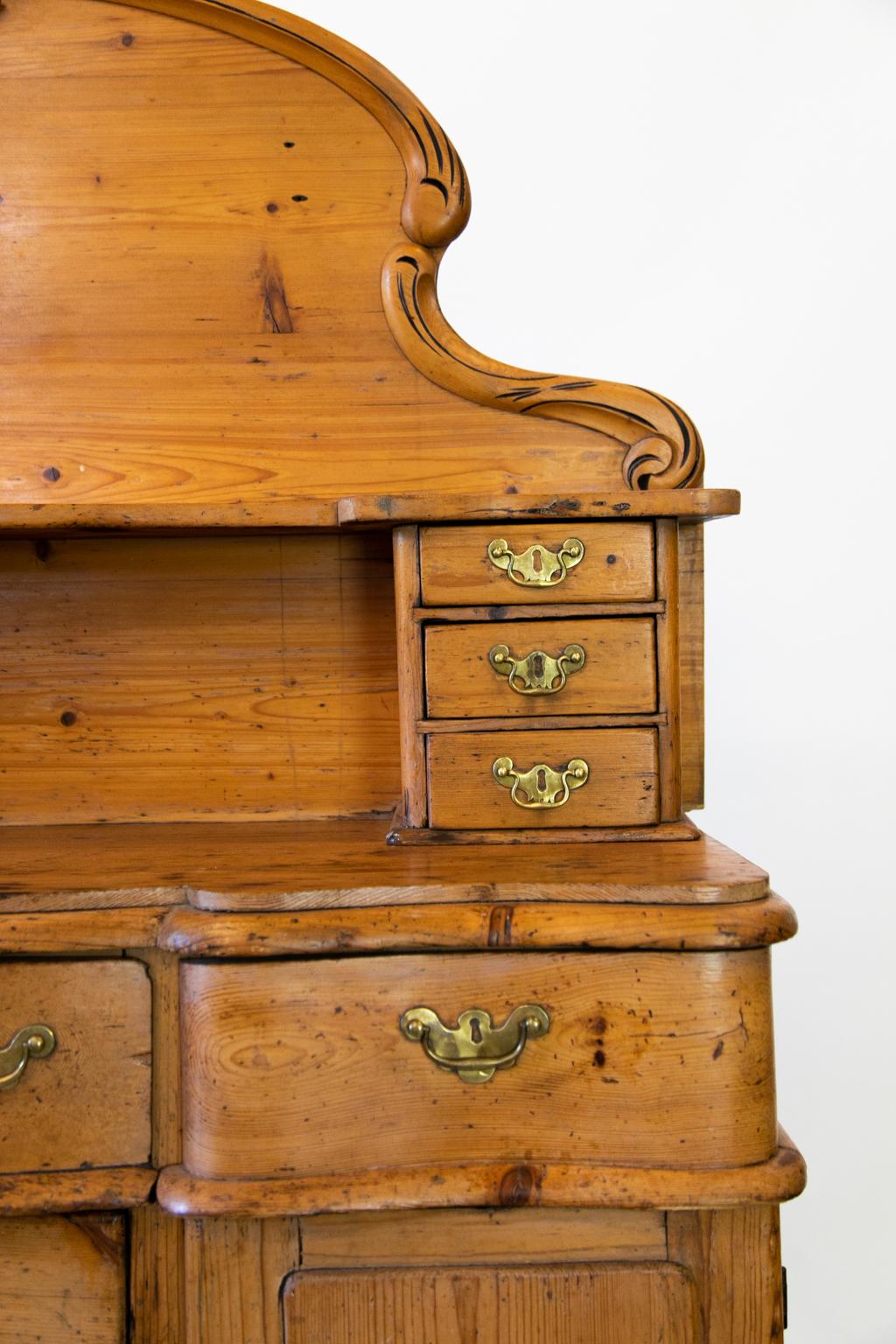 English pine sideboard, with the top half having six drawers below a shaped shelf. The back has applied carved moldings and a center crest. The lower half has five shaped drawers and two doors with raised panels attached to the frame.
 