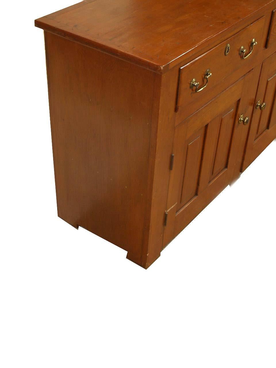 English pine sideboard with two drawers above two doors, the doors with double ''raised'' panels and ball turn latches to keep them shut; interior with an open area on the left and shelf on the right. A good feature of this piece is that it is quite