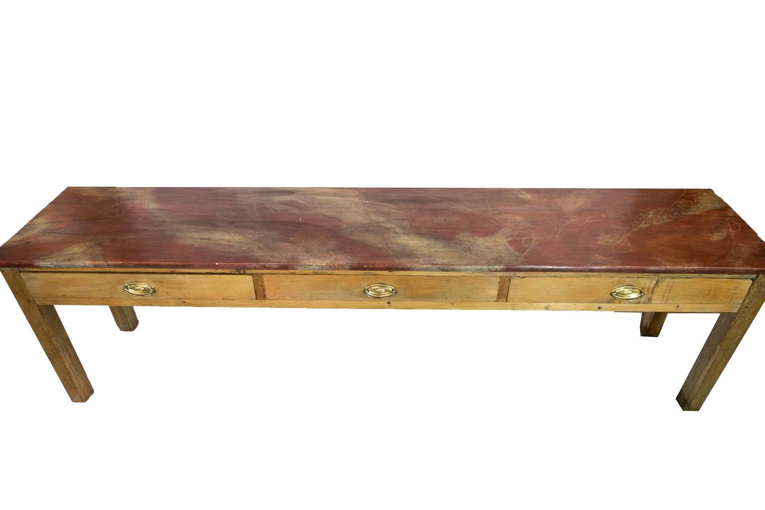 The top of this English pine sideboard/serving table was faux patented circa 1980 to resemble Rojo Alicante marble. The legs are made of oak with exposed double peg construction and have pencil post chamfers on all four sides.
 