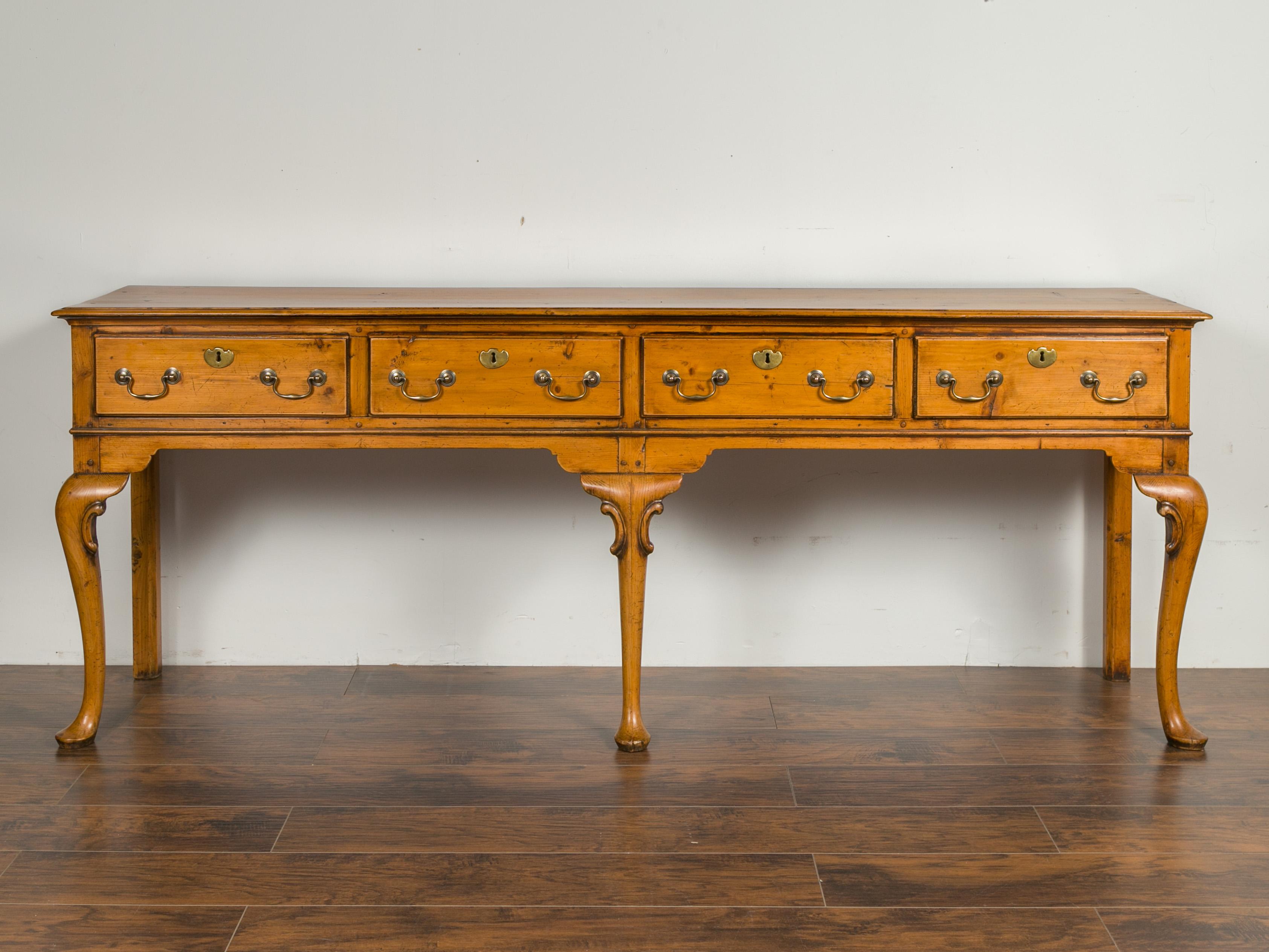 An English pine sideboard from the early 20th century, with four drawers and cabriole legs. Crafted in England during the early 1900s, this pine sideboard, which used to be a dresser base, features a rectangular top with beveled edges, sitting above